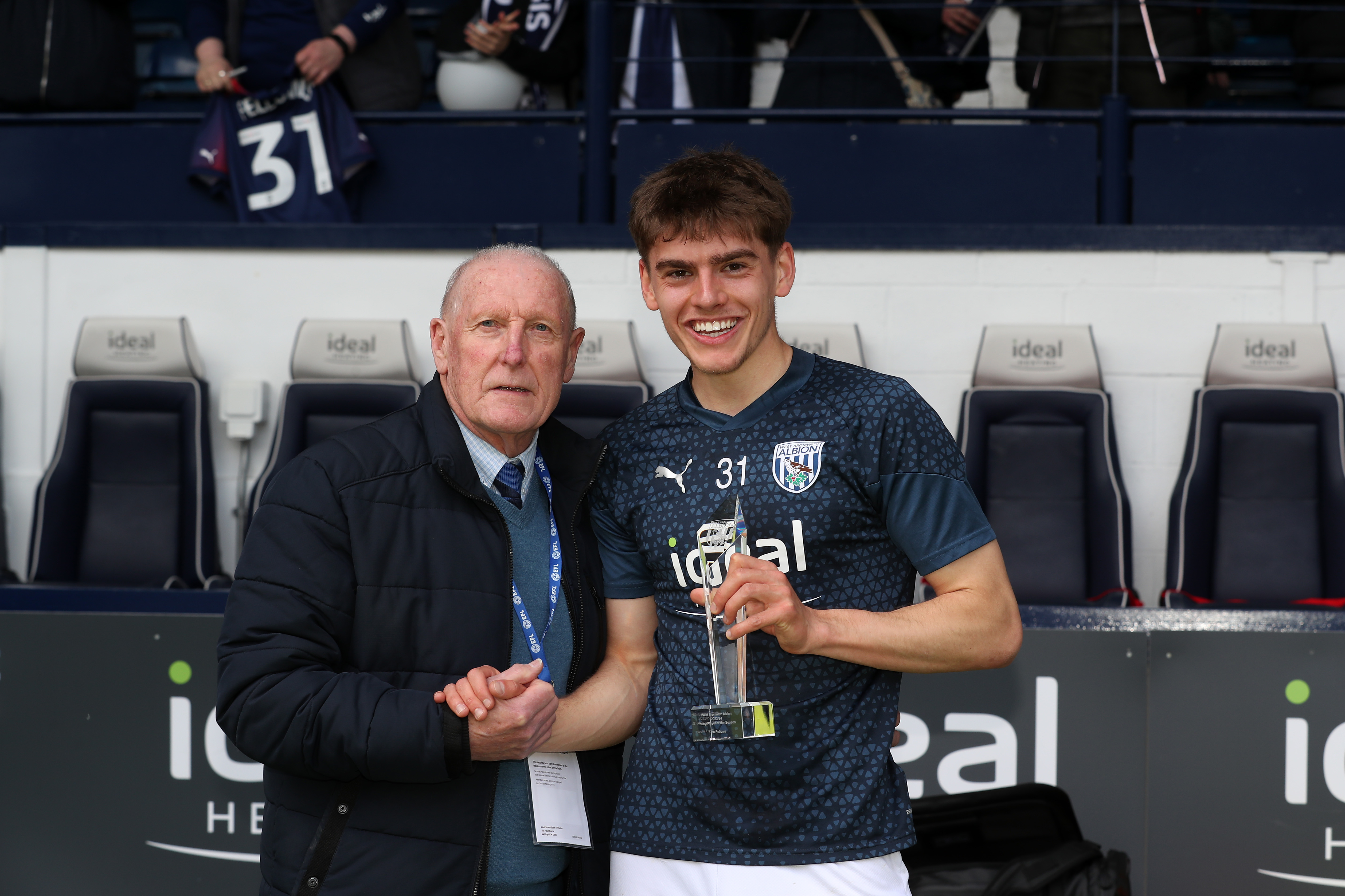 Tony Brown presents Tom Fellows with the 2023/24 Young Player of the Season award in the dugout at The Hawthorns