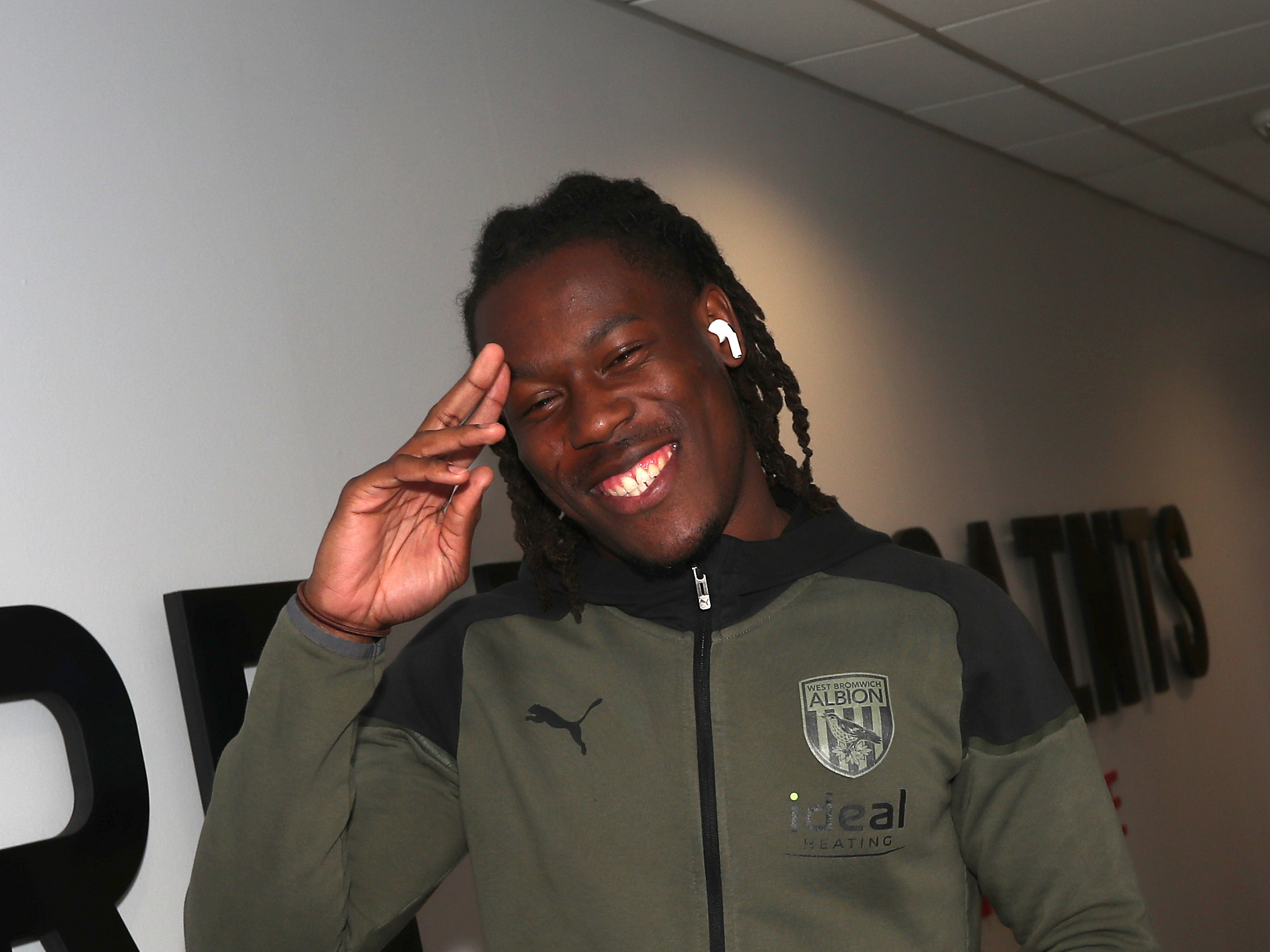 Brandon Thomas-Asante smiling at the camera as he arrives for a game wearing his Albion tracksuit 