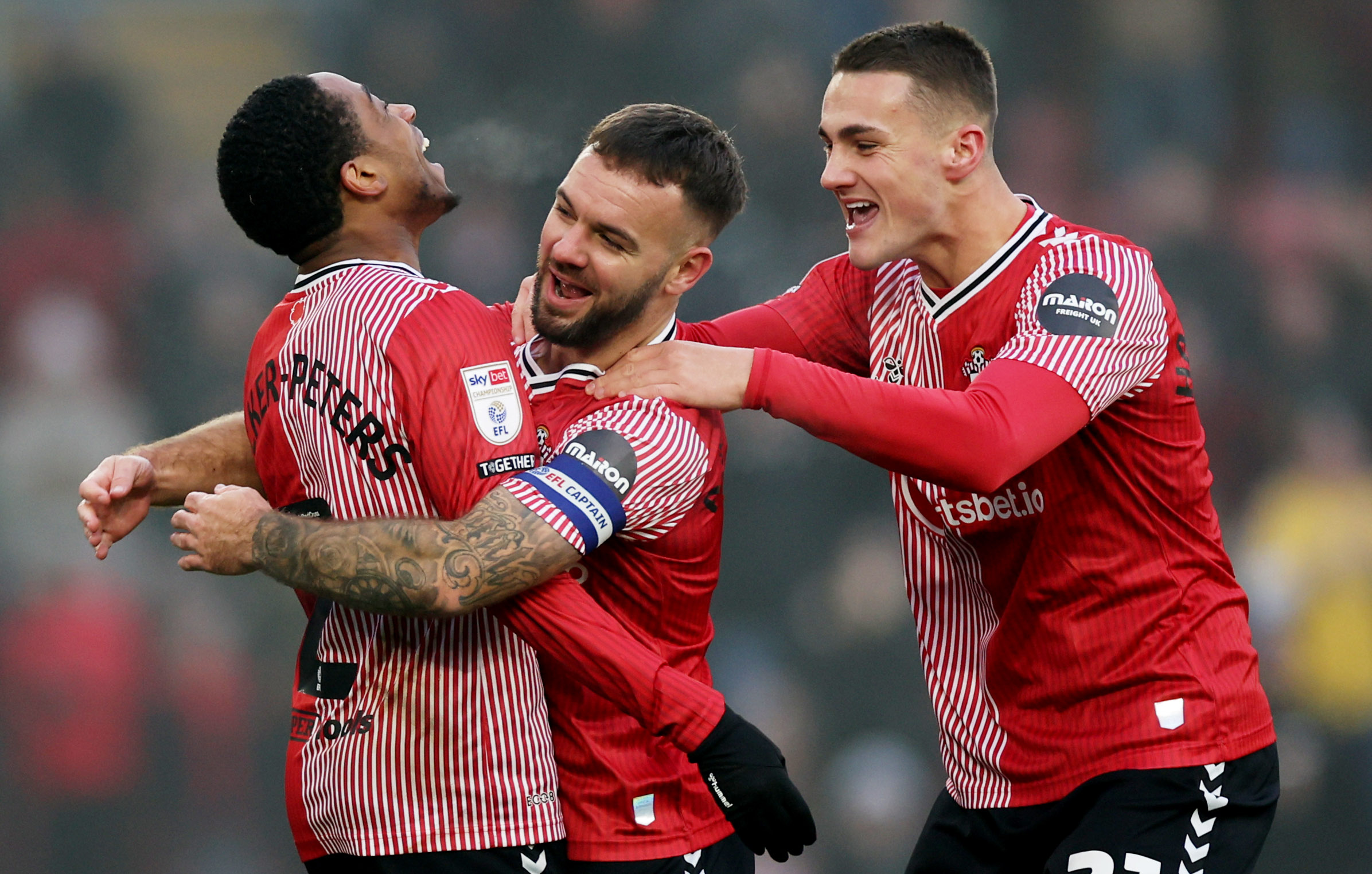 Kyle Walker-Peters, Adam Armstrong and Taylor Harwood-Bellis celebrate a Southampton goal while wearing their home kit 