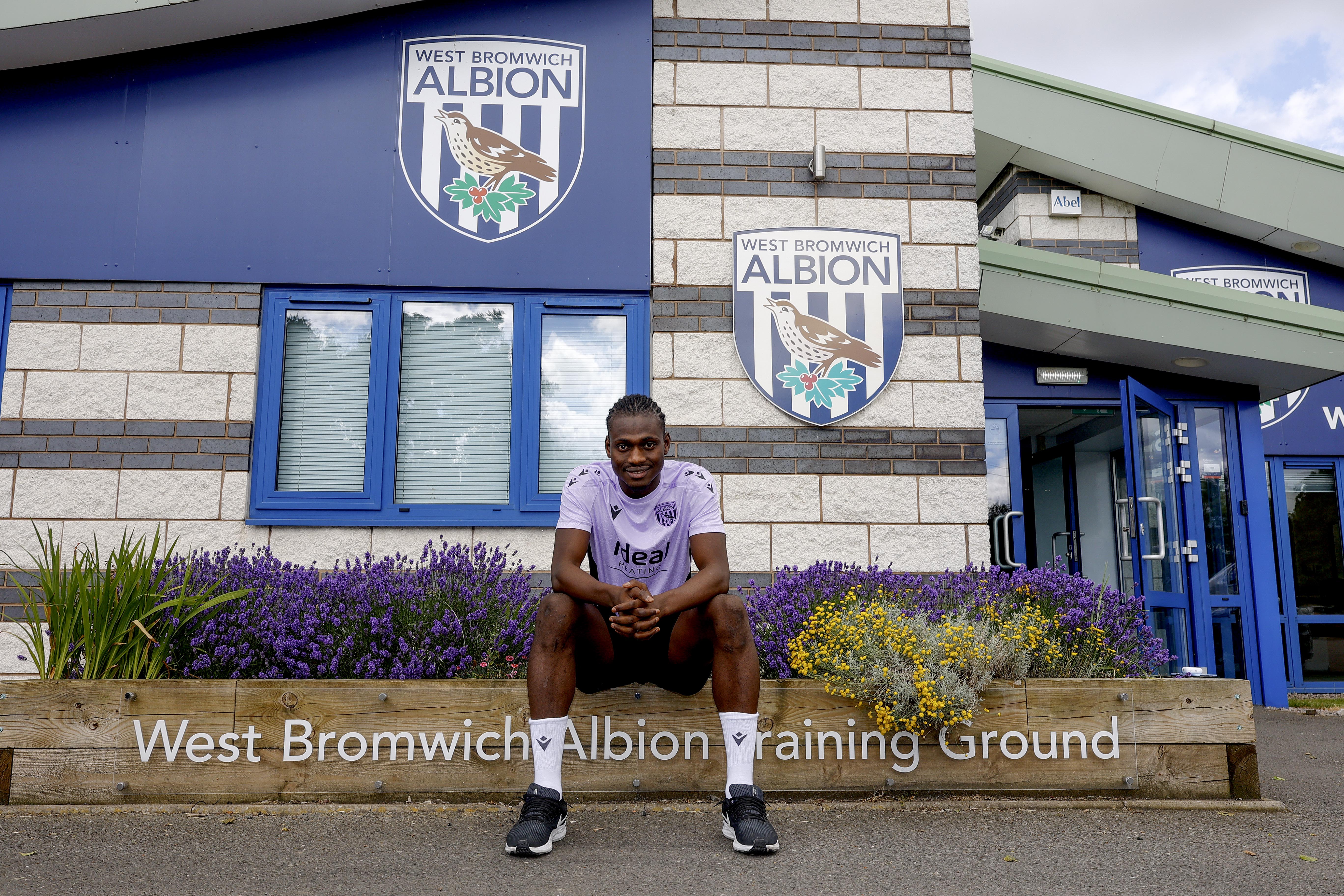 Ousmane Diakité smiling at the camera while sat outside the training ground entrance 