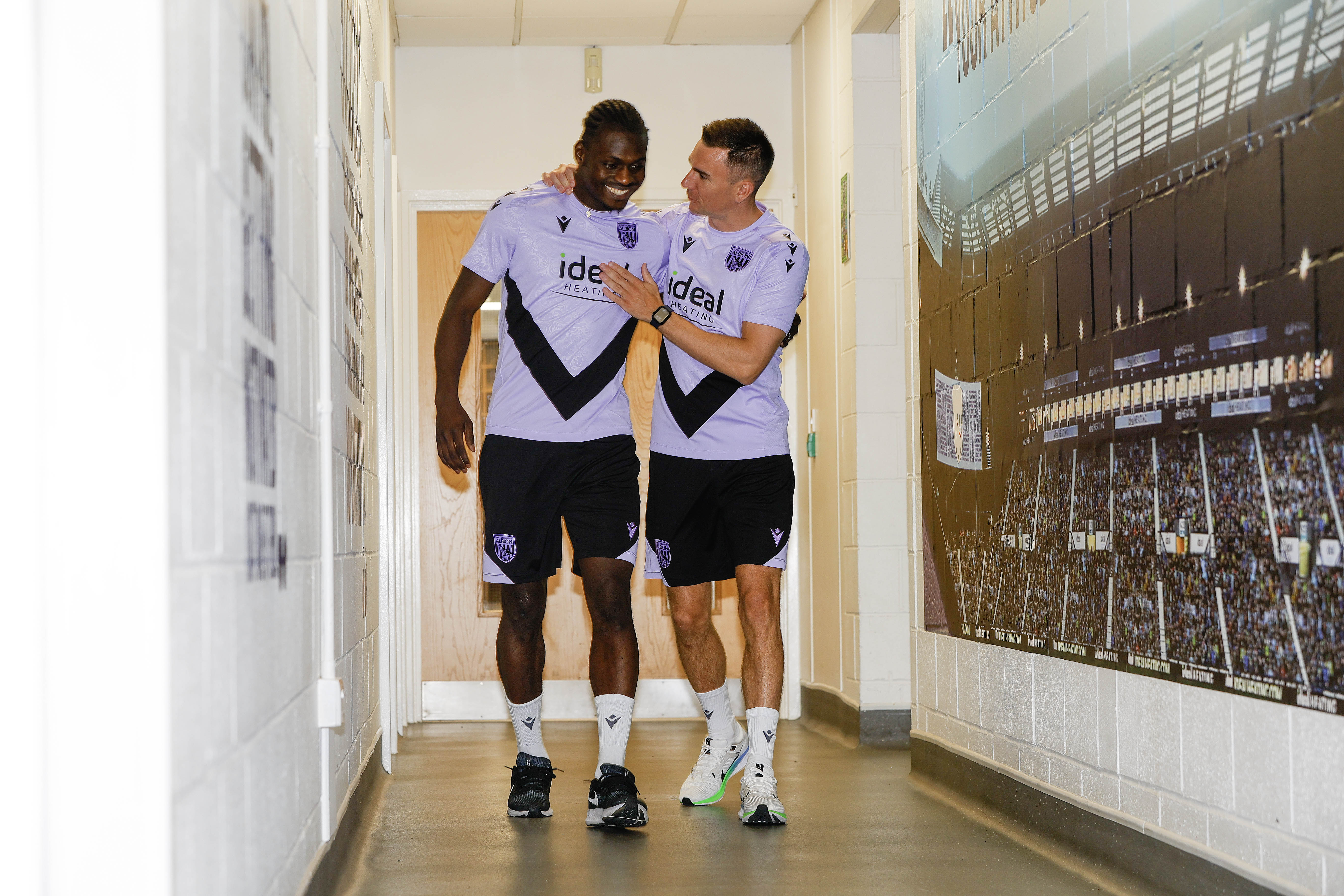 Ousmane Diakité and Jed Wallace laughing while walking down a corridor 