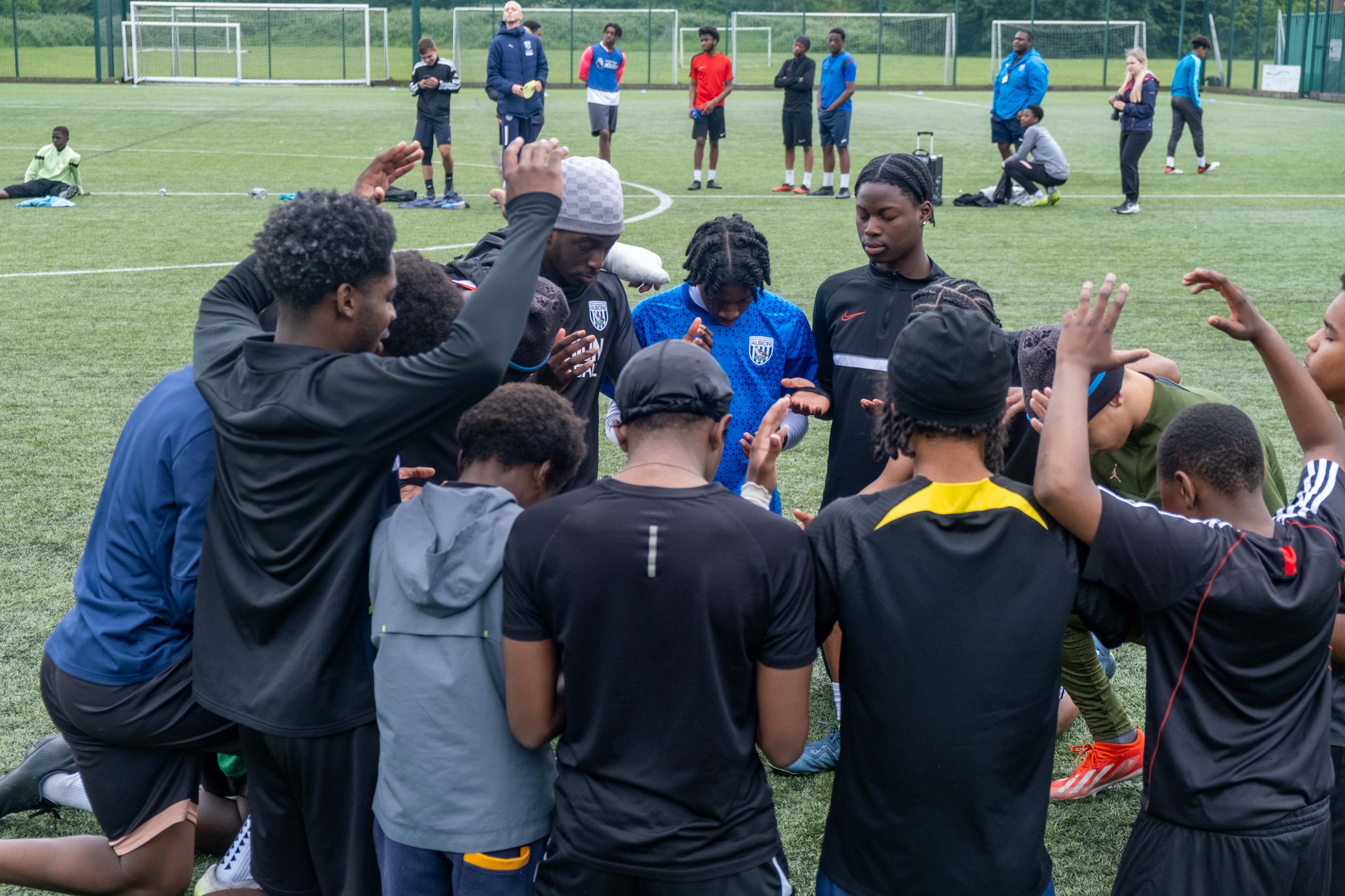 Non bibs team in a pray circle.