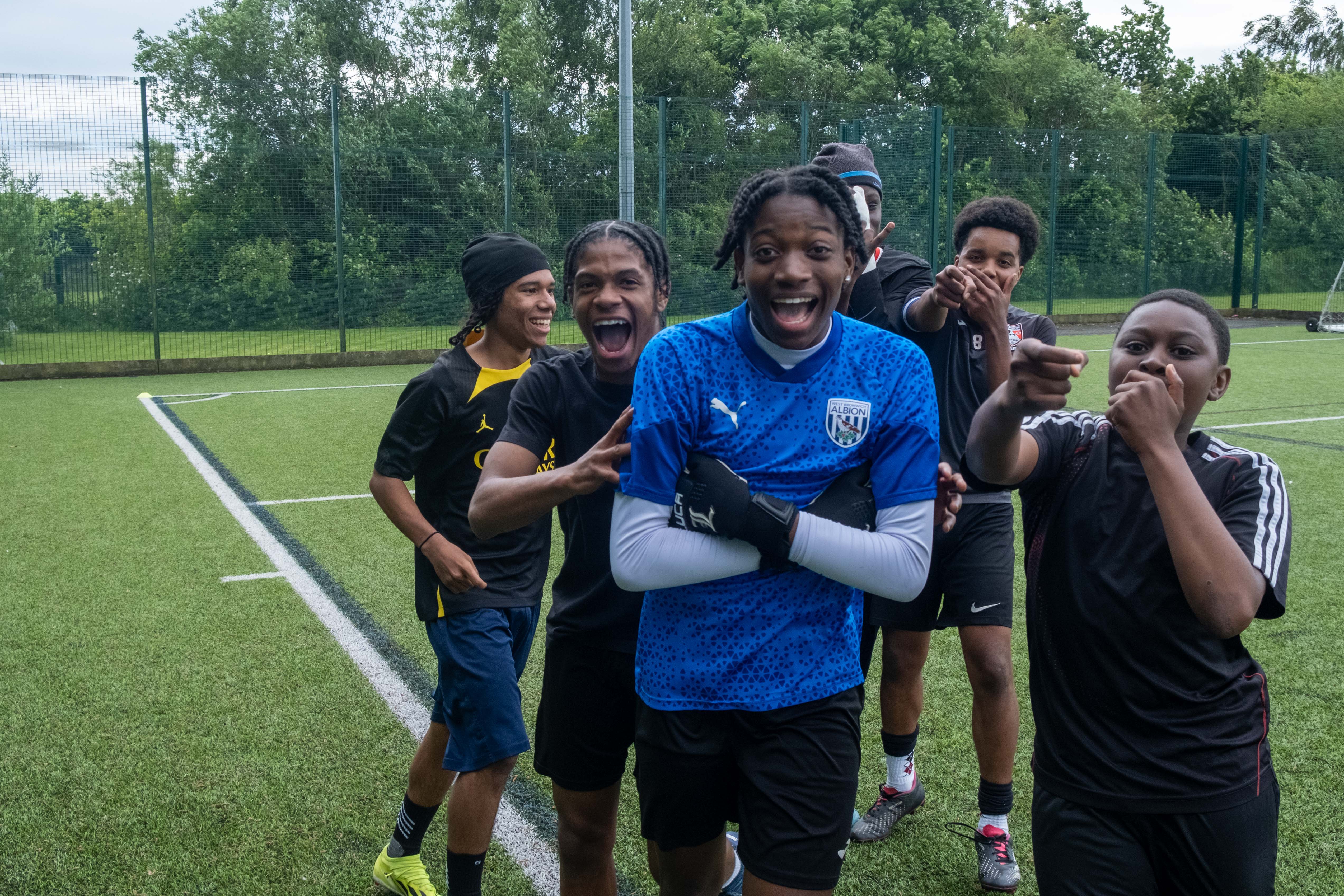 Non bib team celebrate a goal, with players doing various celebrations.