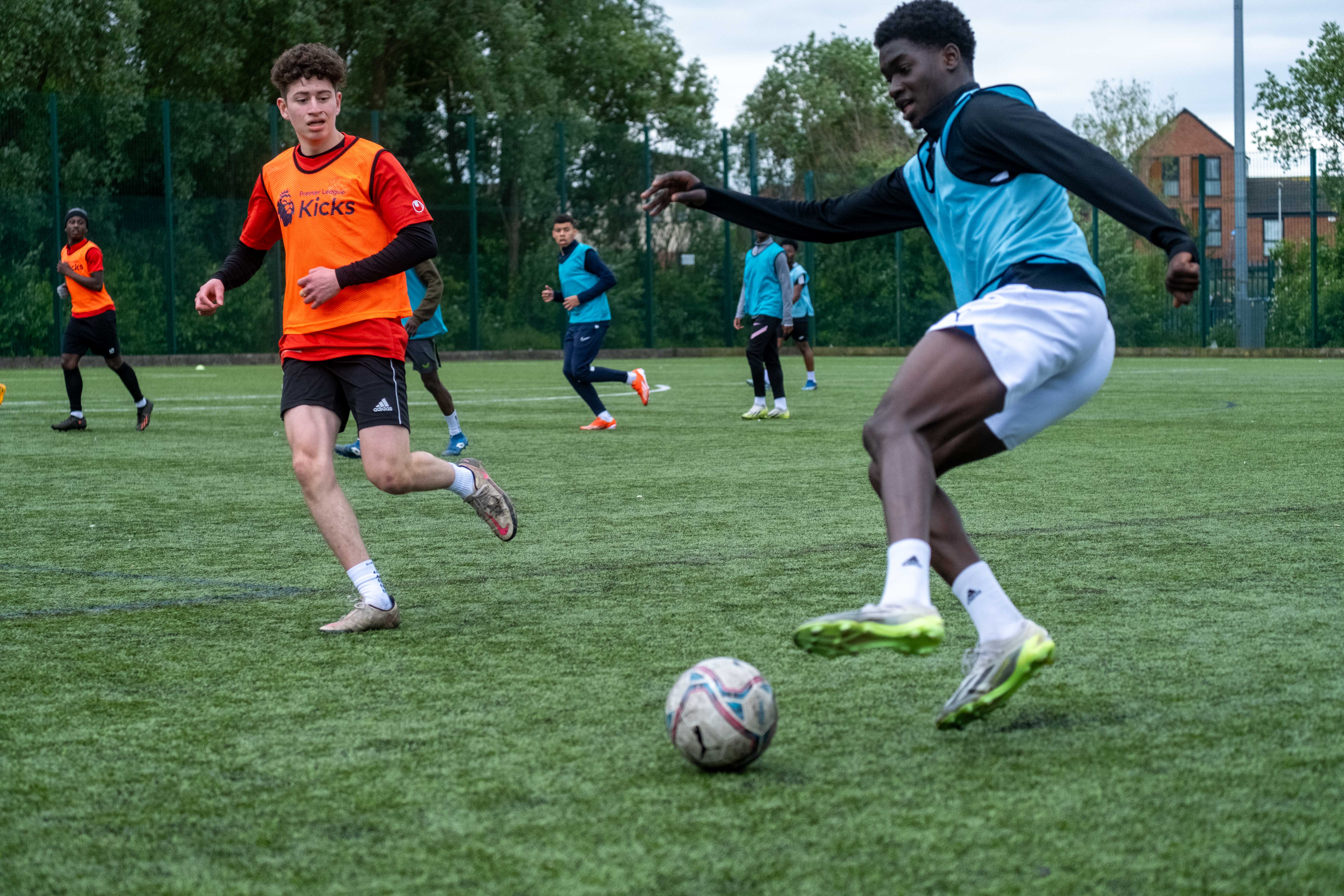 Player (Aqua blue)gaining control of the ball to make a cross, with defender (Orange) takes to cut him off.