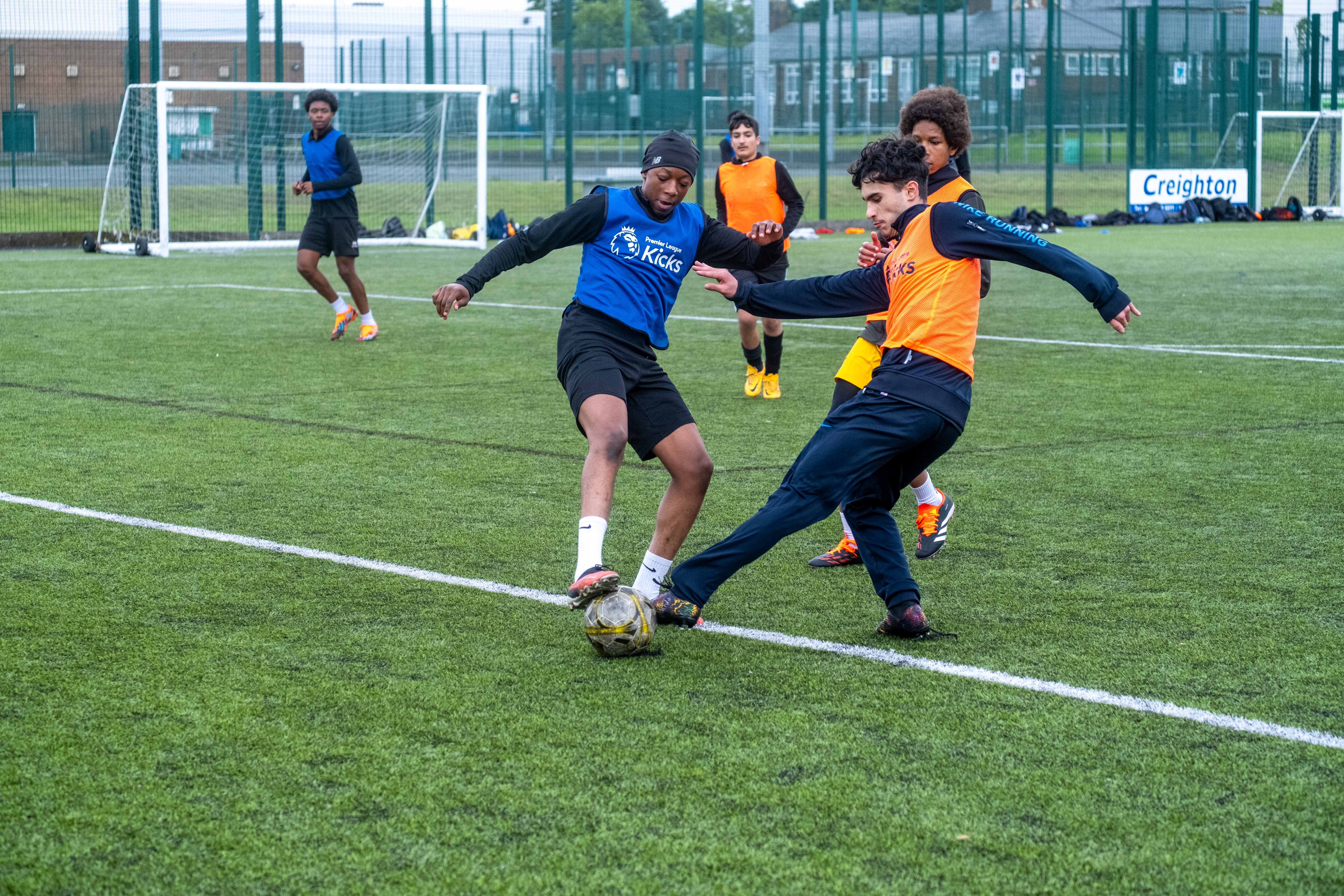 Two players (Dark blue & Orange) challenge for the ball.