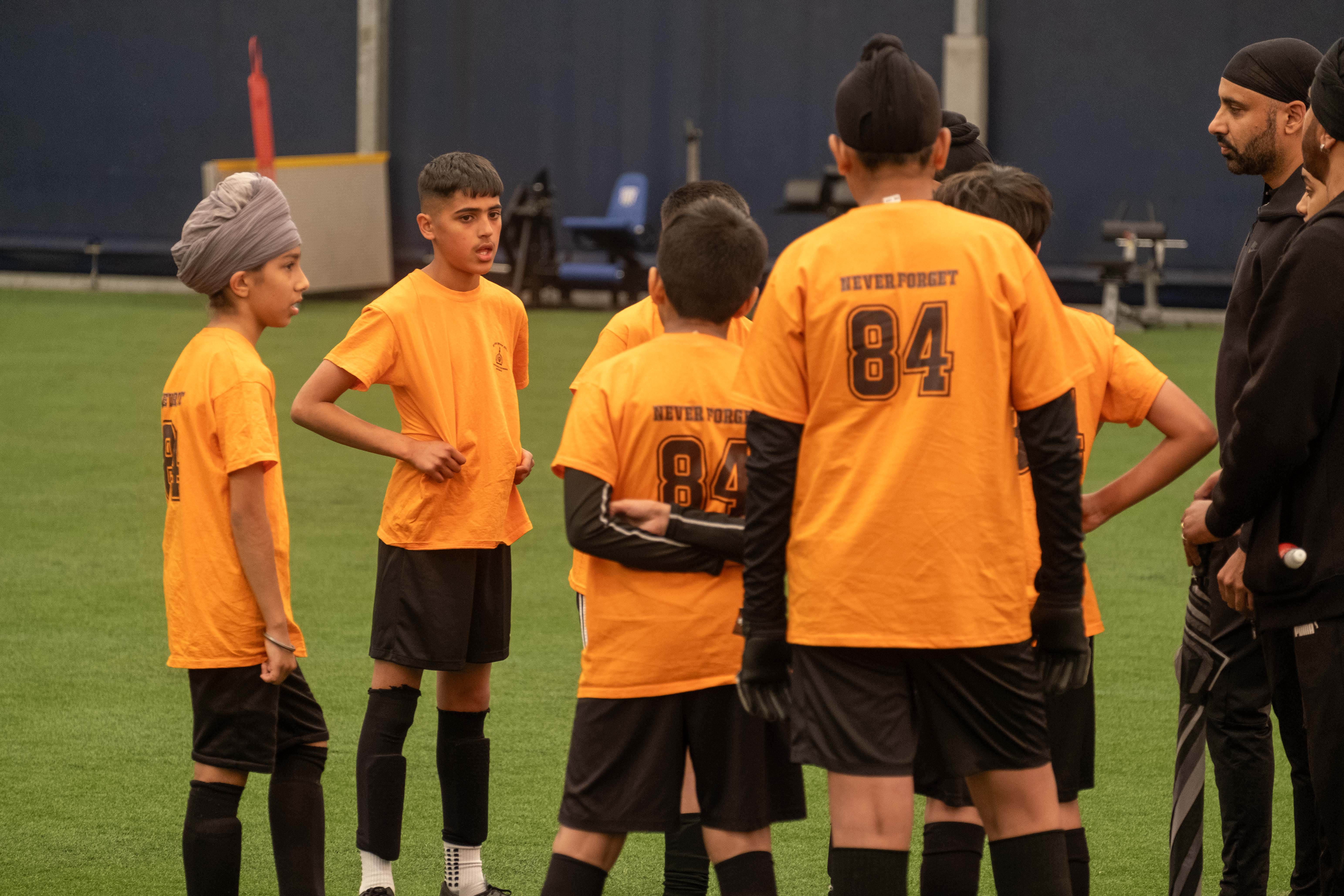 A team wearing orange gather in a huddle during our South Asian Emerging Talent Festival in the Academy Dome.