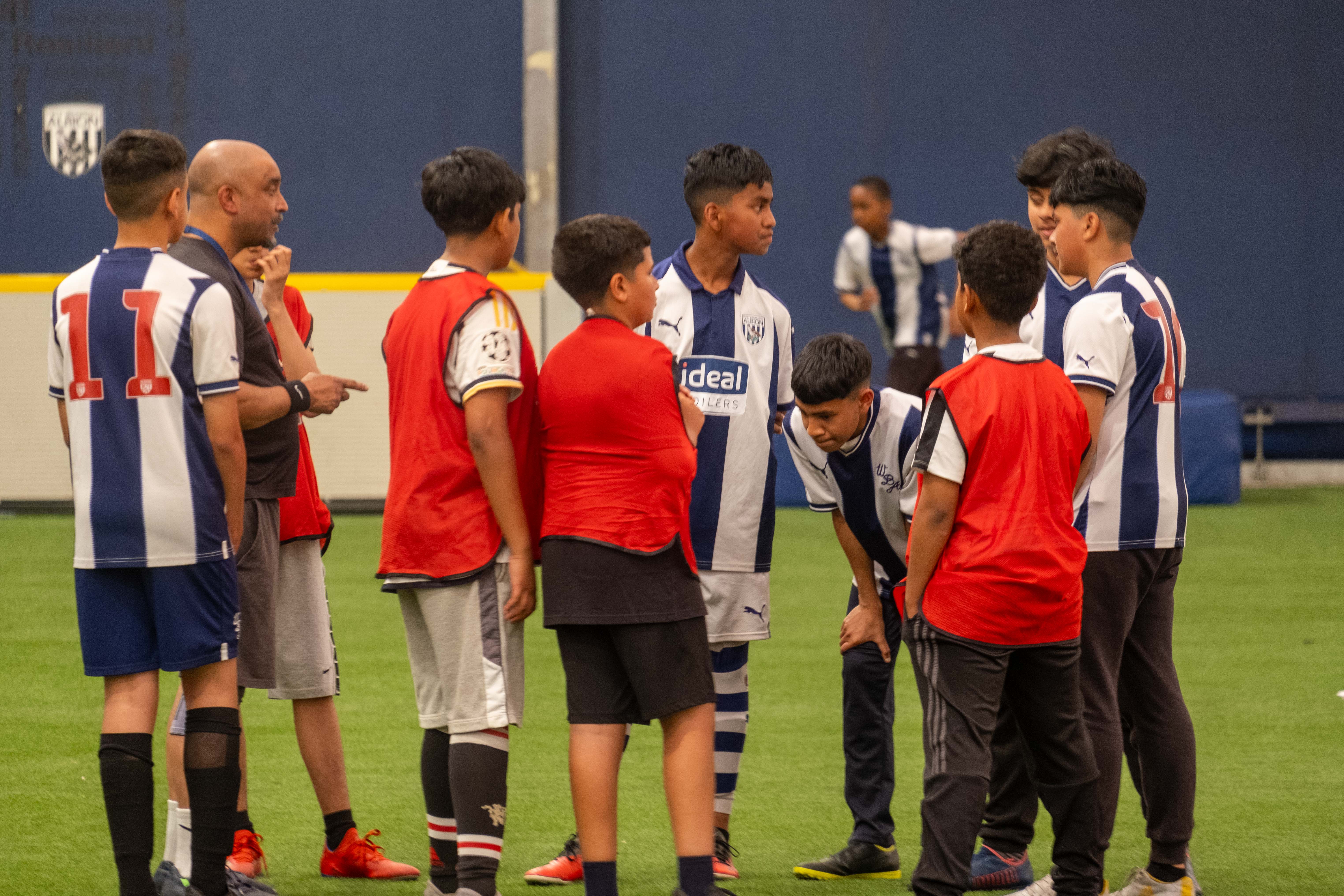 A group of players mainly decked in West Brom home shirts talk during the South Asian Emerging Talent Festival in the Academy Dome.