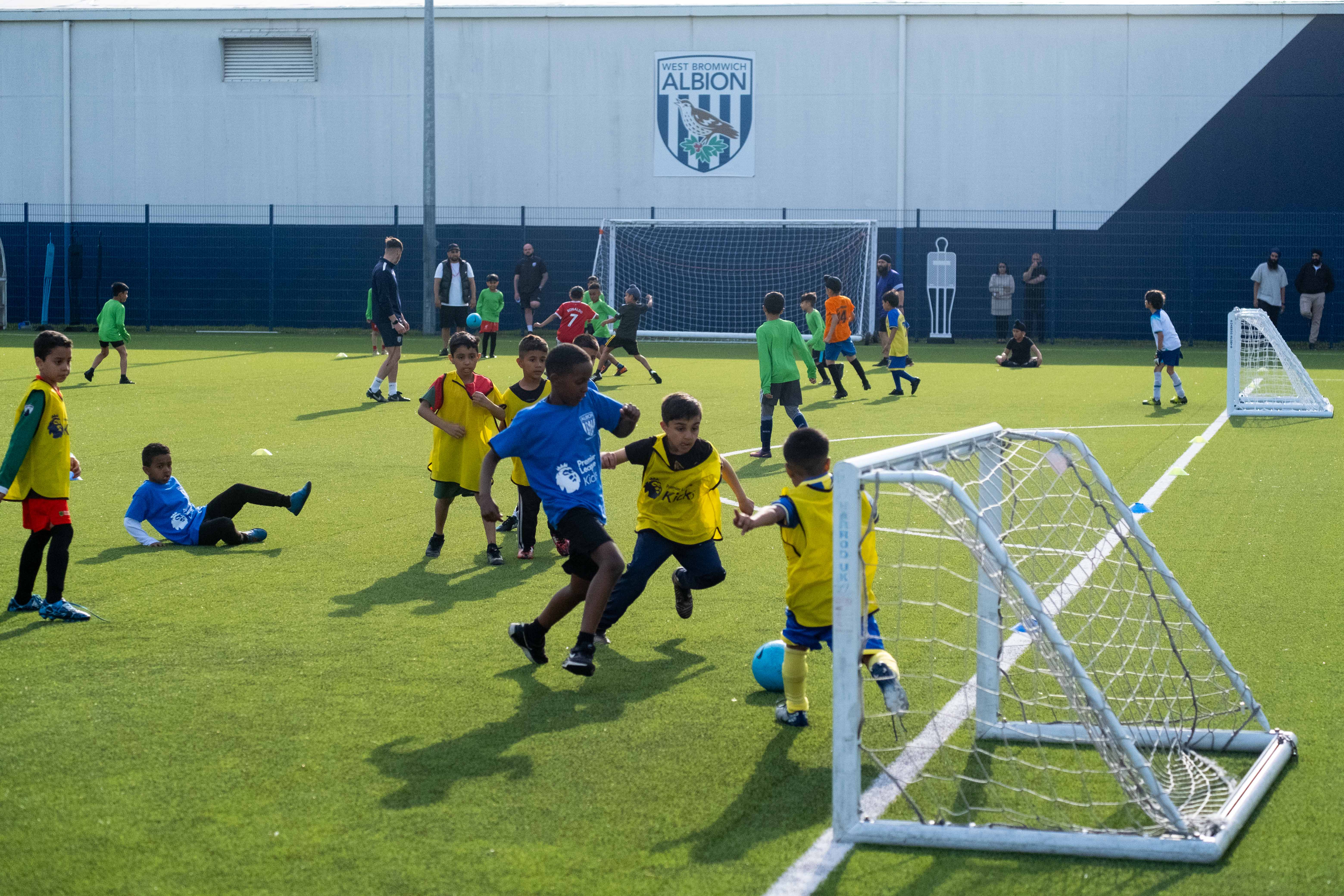 Players wearing yellow bibs try to stop a player in a blue bib from scoring during our South Asian Emerging Talent Festival on the Academy pitch.