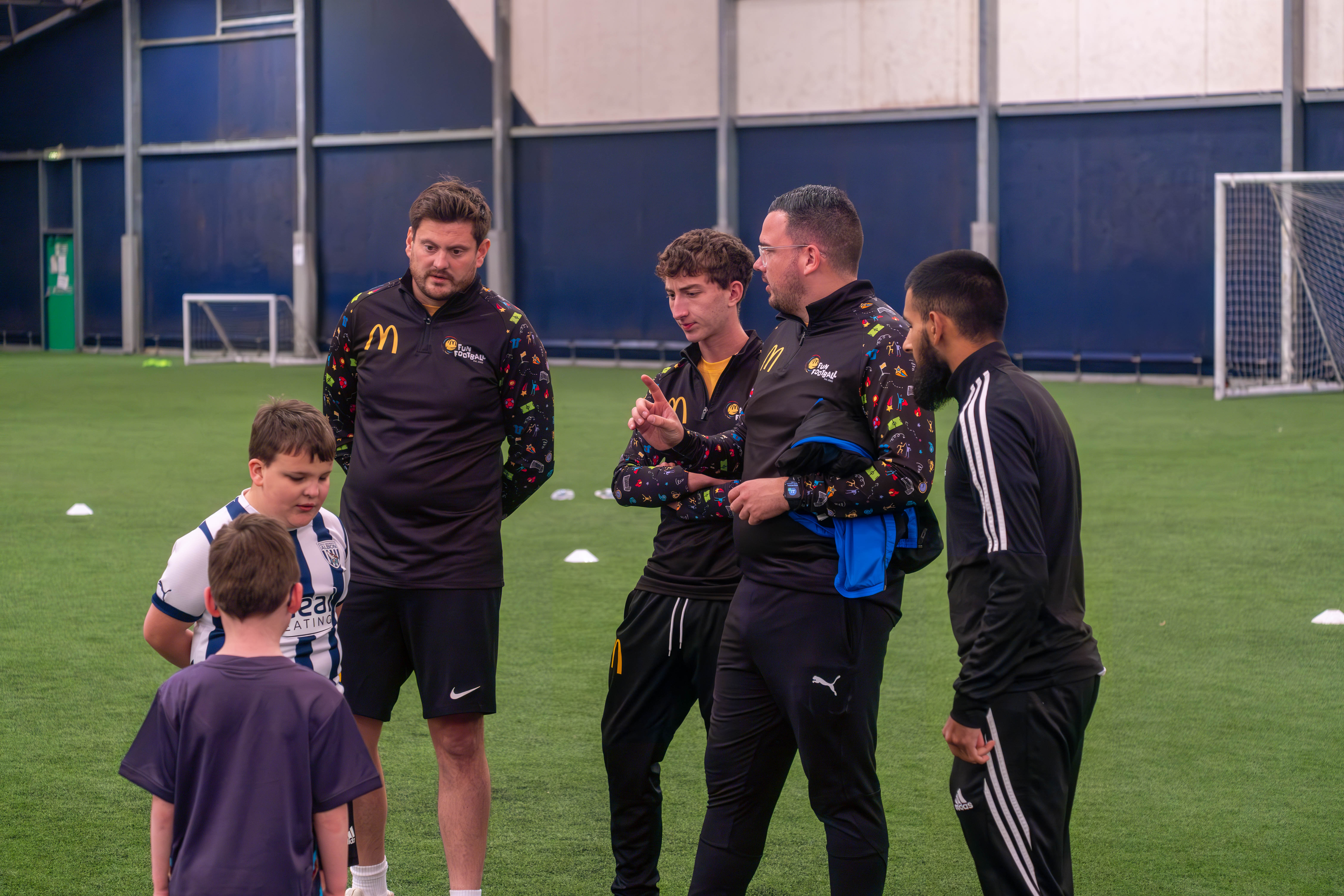 Eesa interacts with young footballers whilst stood next to disability sports coach Chris Winston during the McDonald's Fun Football Session.