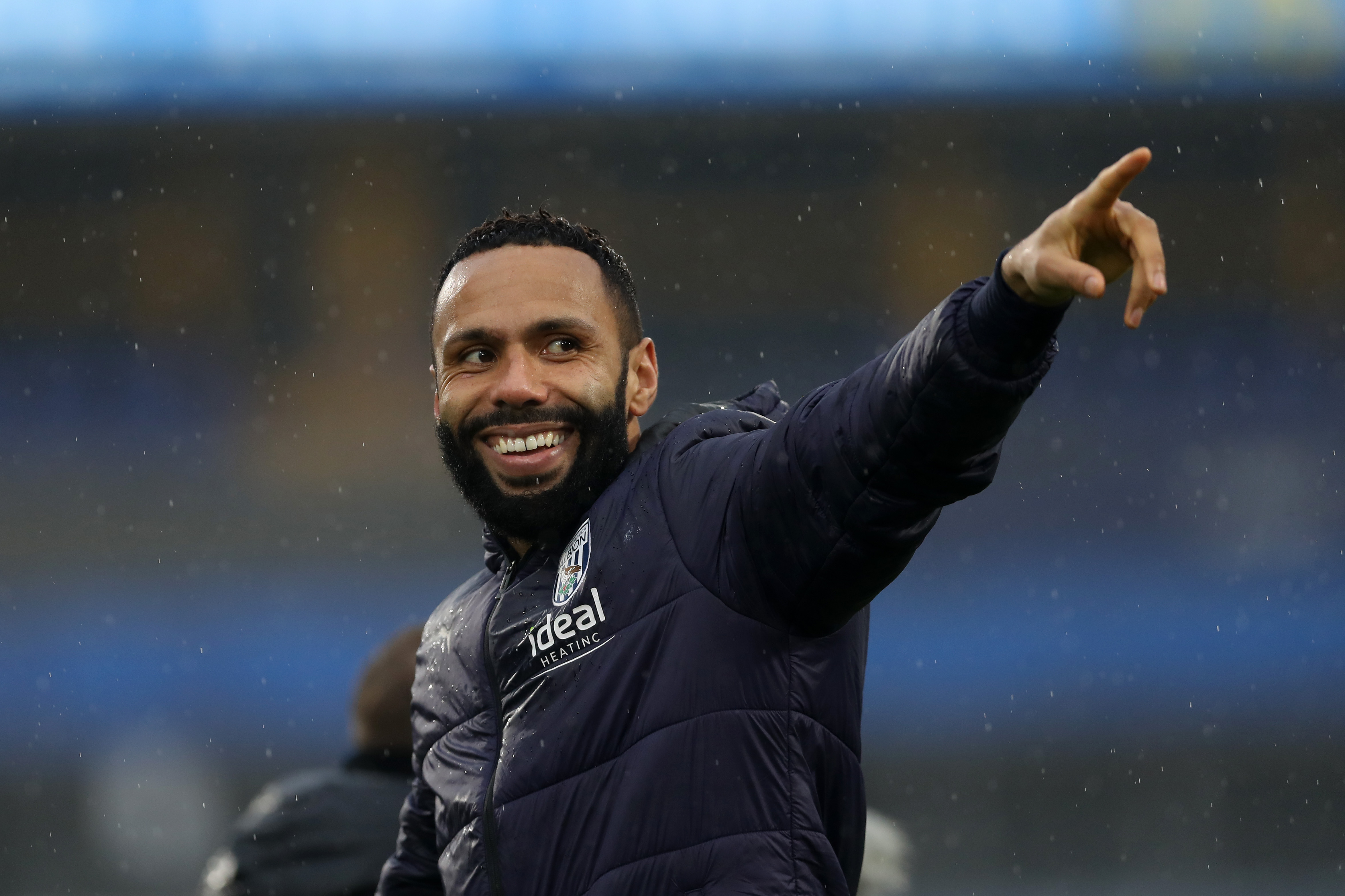 Kyle Bartley smiling and pointing while wearing an Albion coat