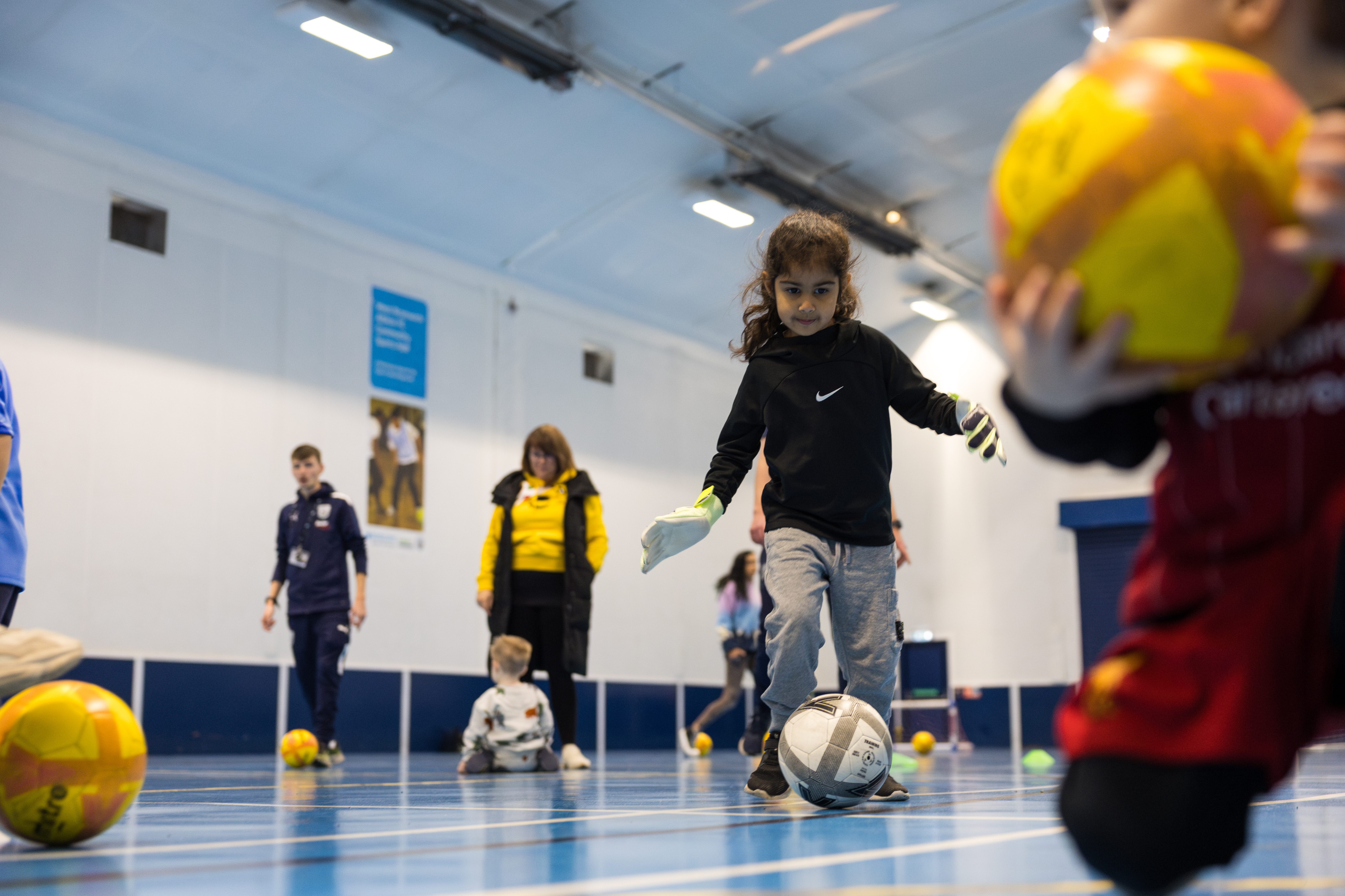 Khadijah dribbles a ball forwards towards the camera.