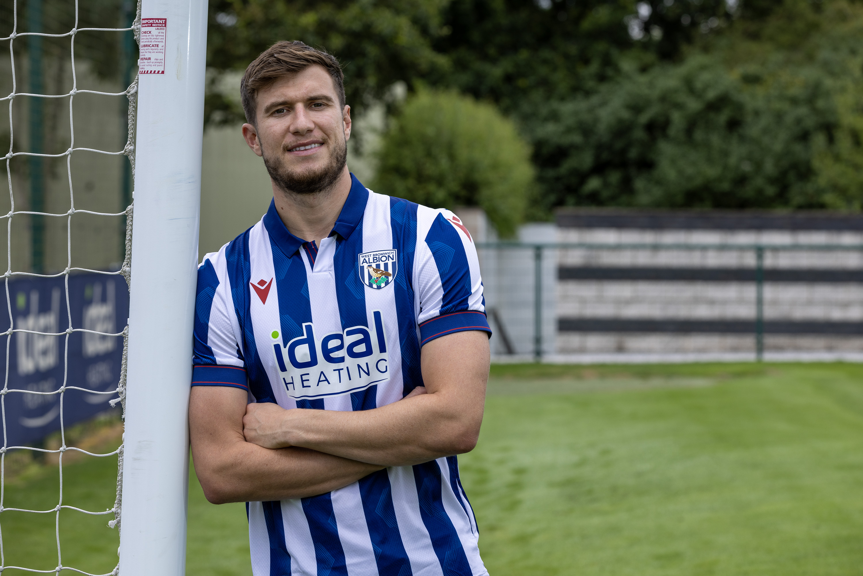 Paddy McNair smiling at the camera while stood up against a goal post in a home shirt 