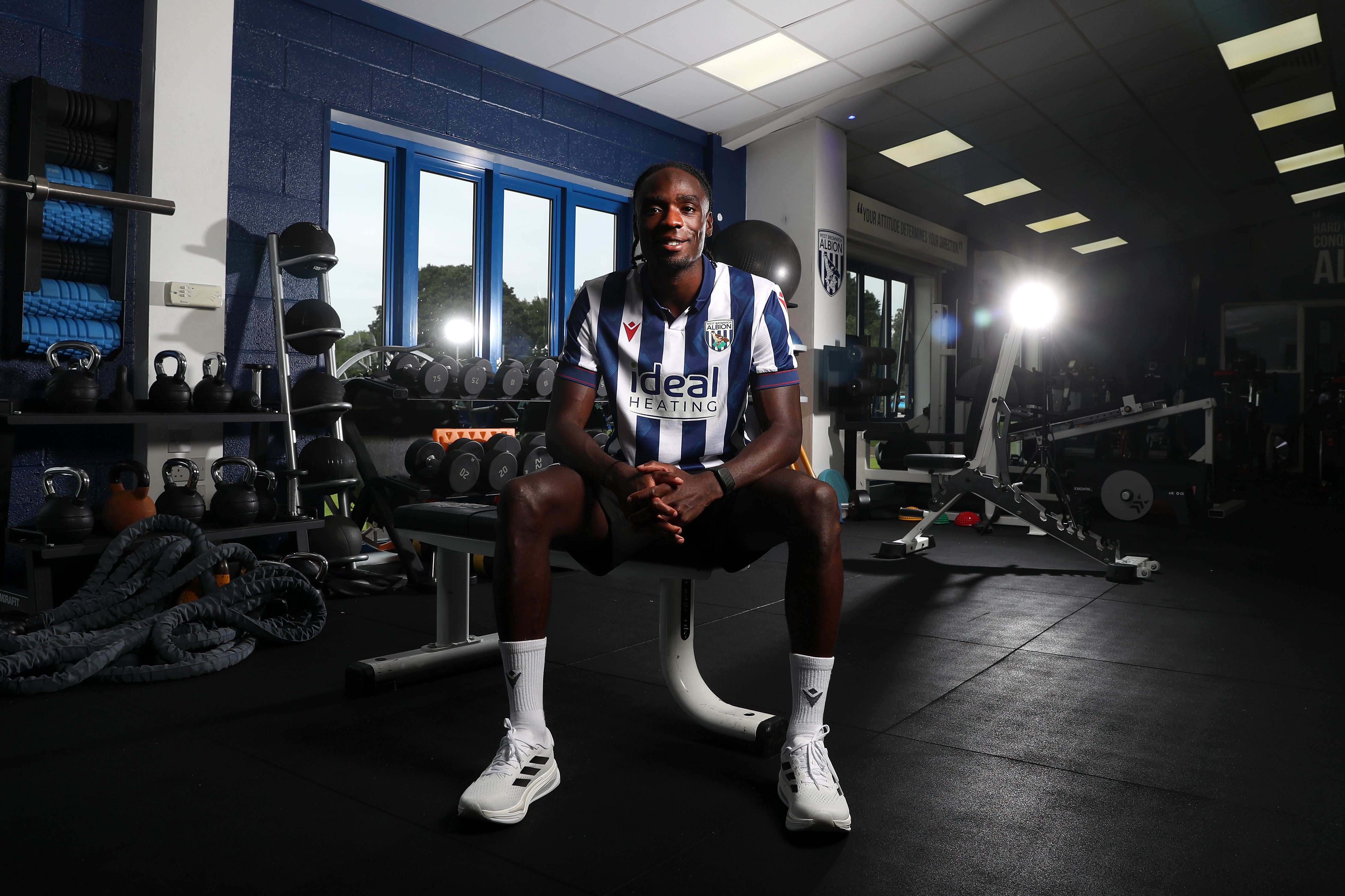 Devante Cole sat in the gym in the home shirt smiling at the camera 