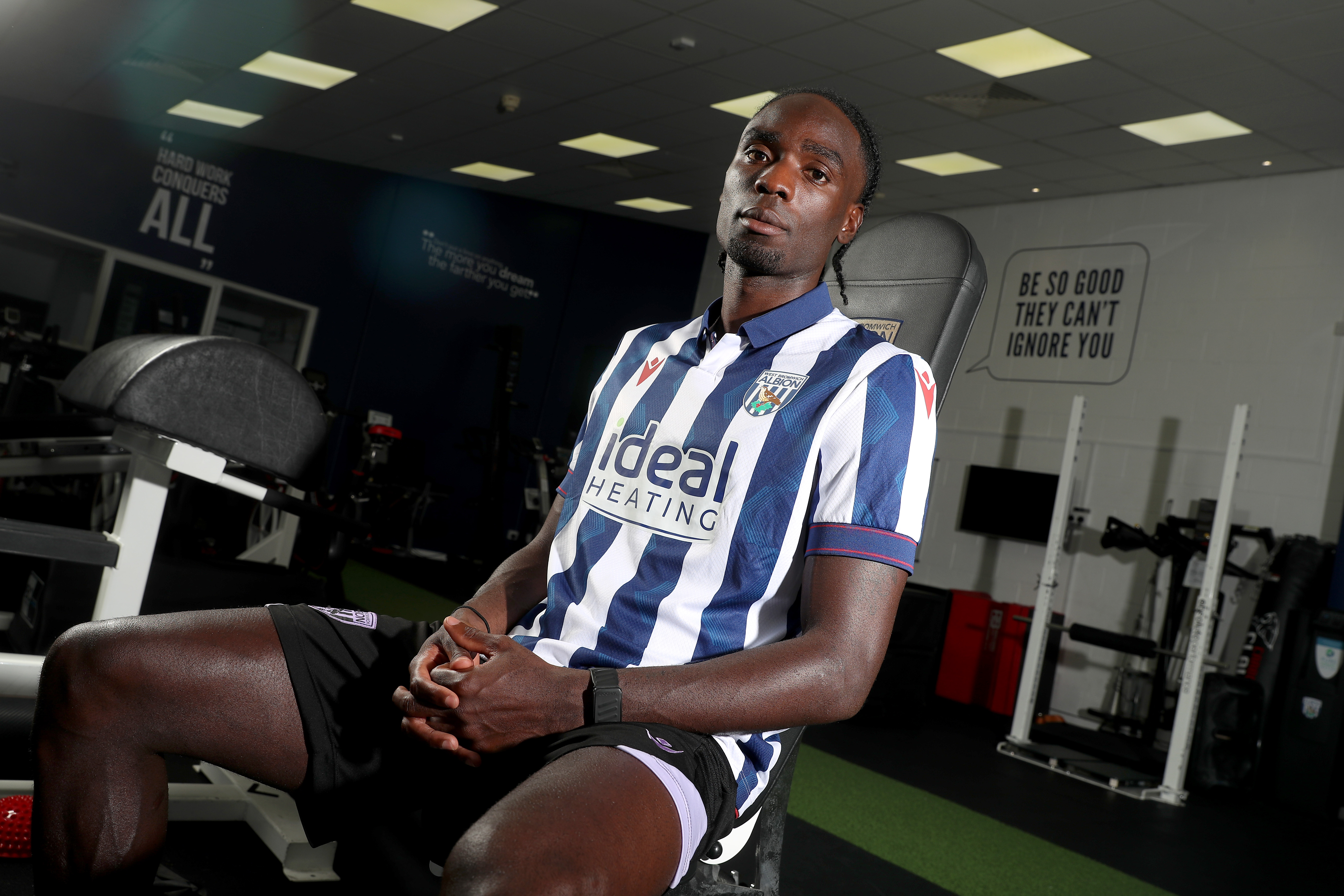 Devante Cole staring at the camera in a home shirt while sat in the gym 