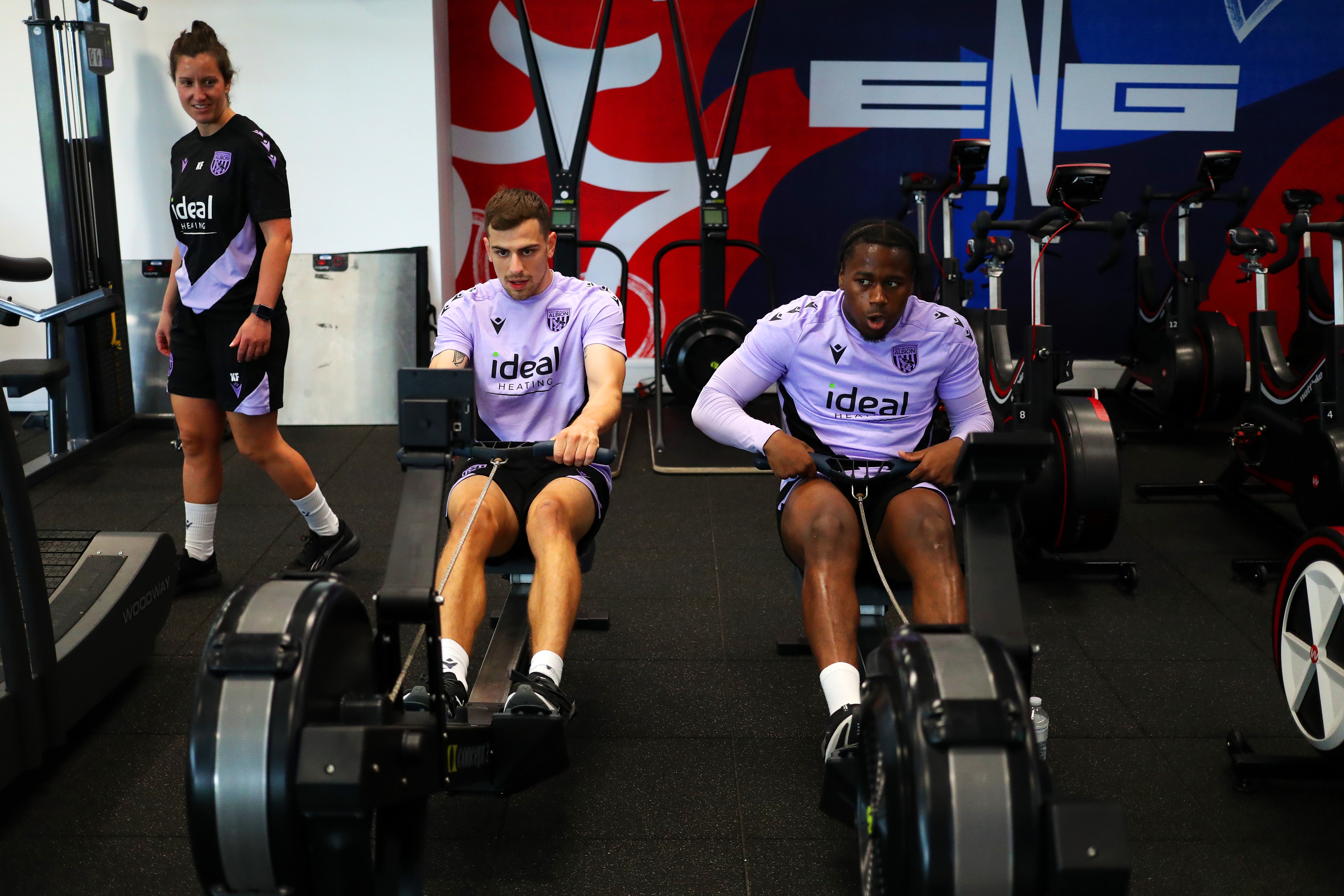 Jayson Molumby and Reyes Cleary on the rowing machine in the gym at St. George's Park