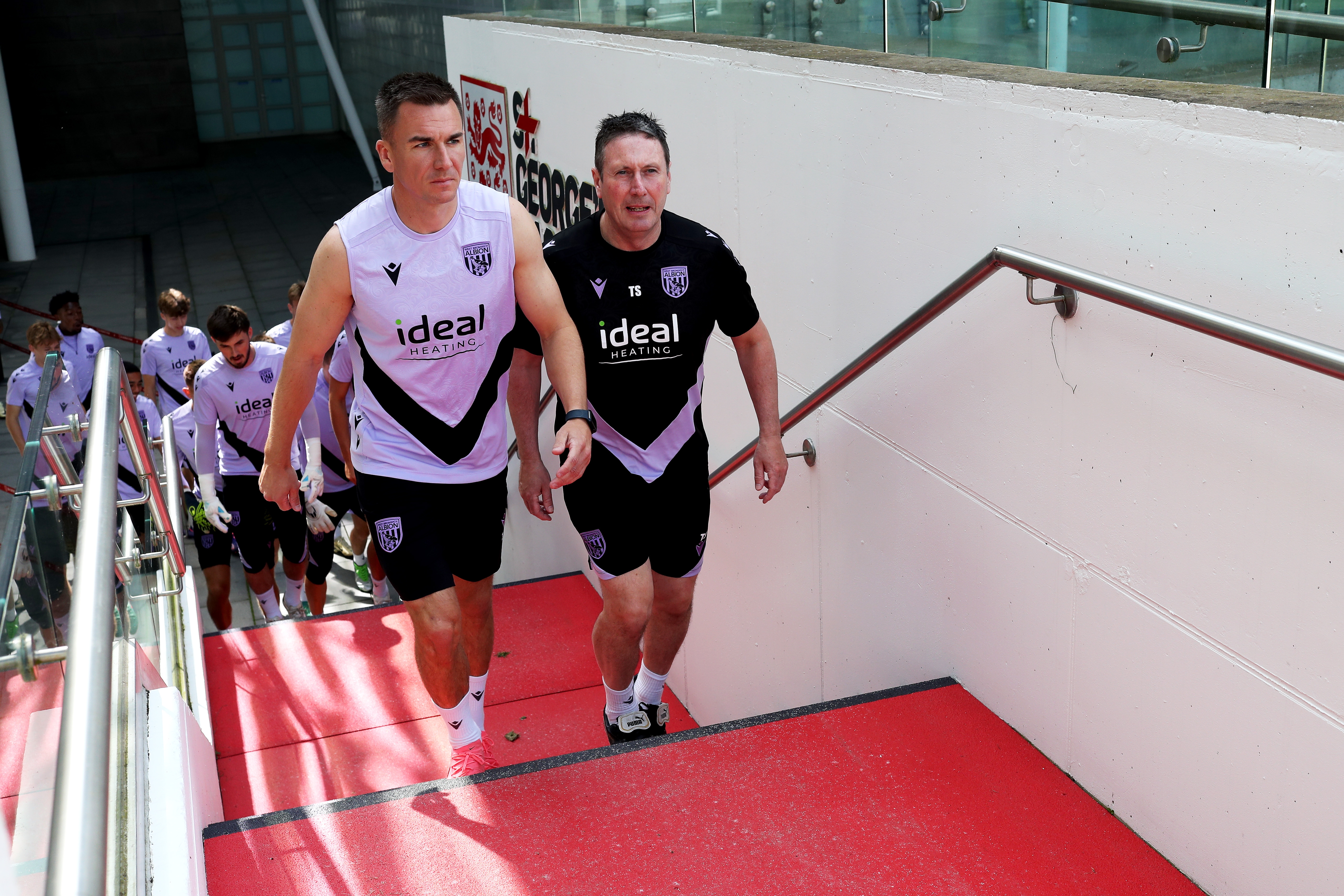 Jed Wallace and Director of Medical Tony Strudwick walking up the steps to the training pitch at St. George's Park