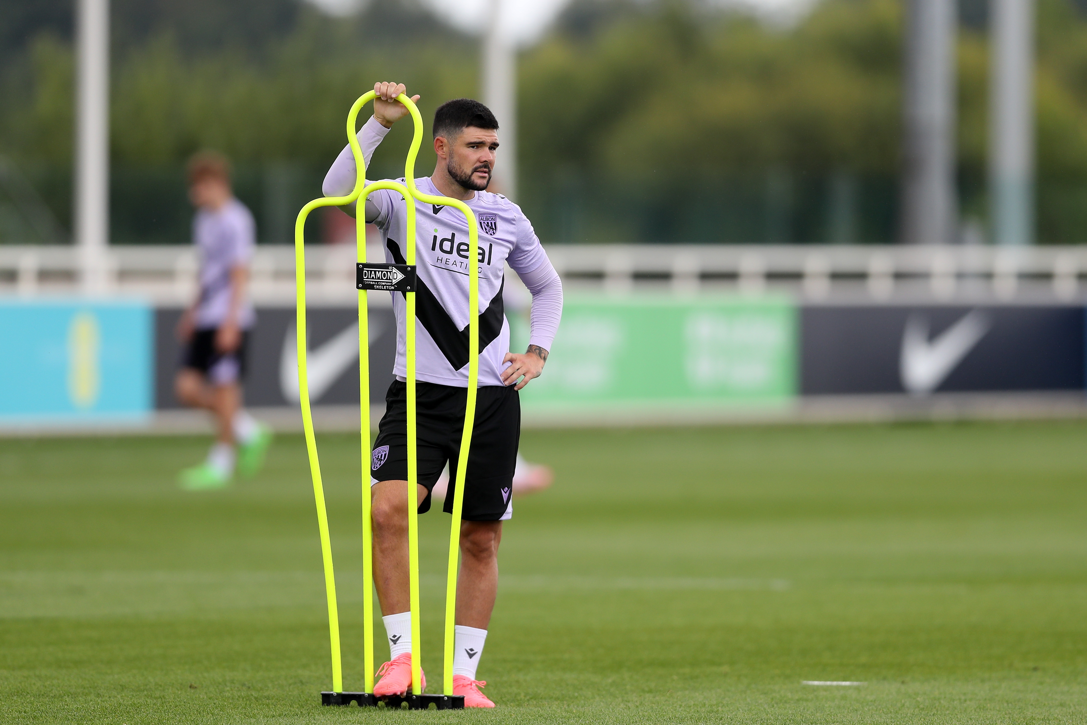 Alex Mowatt stood by a mannequin on the training pitch at St. George's Park