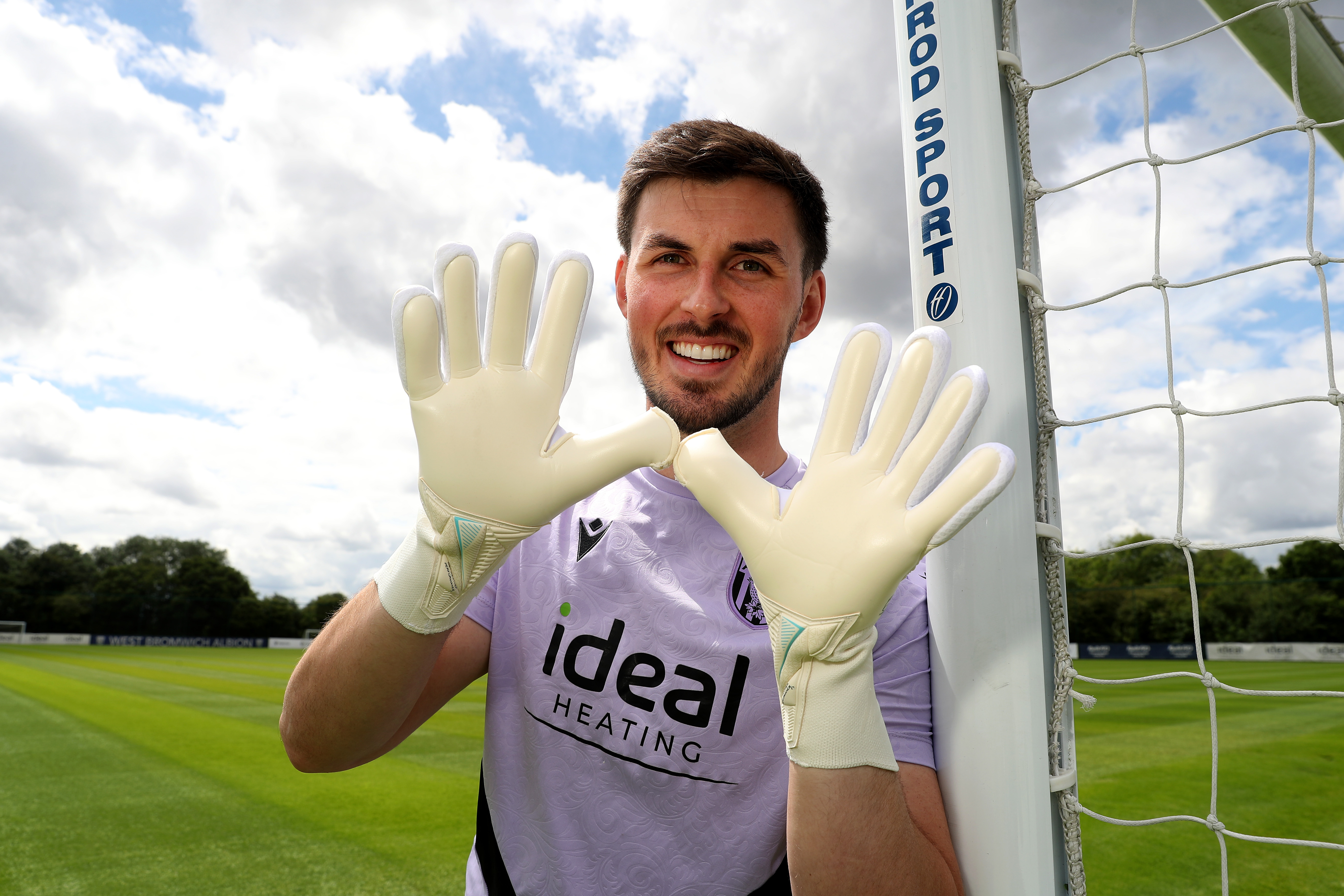 Joe Wildsmith smiling at the camera while holding his gloves up