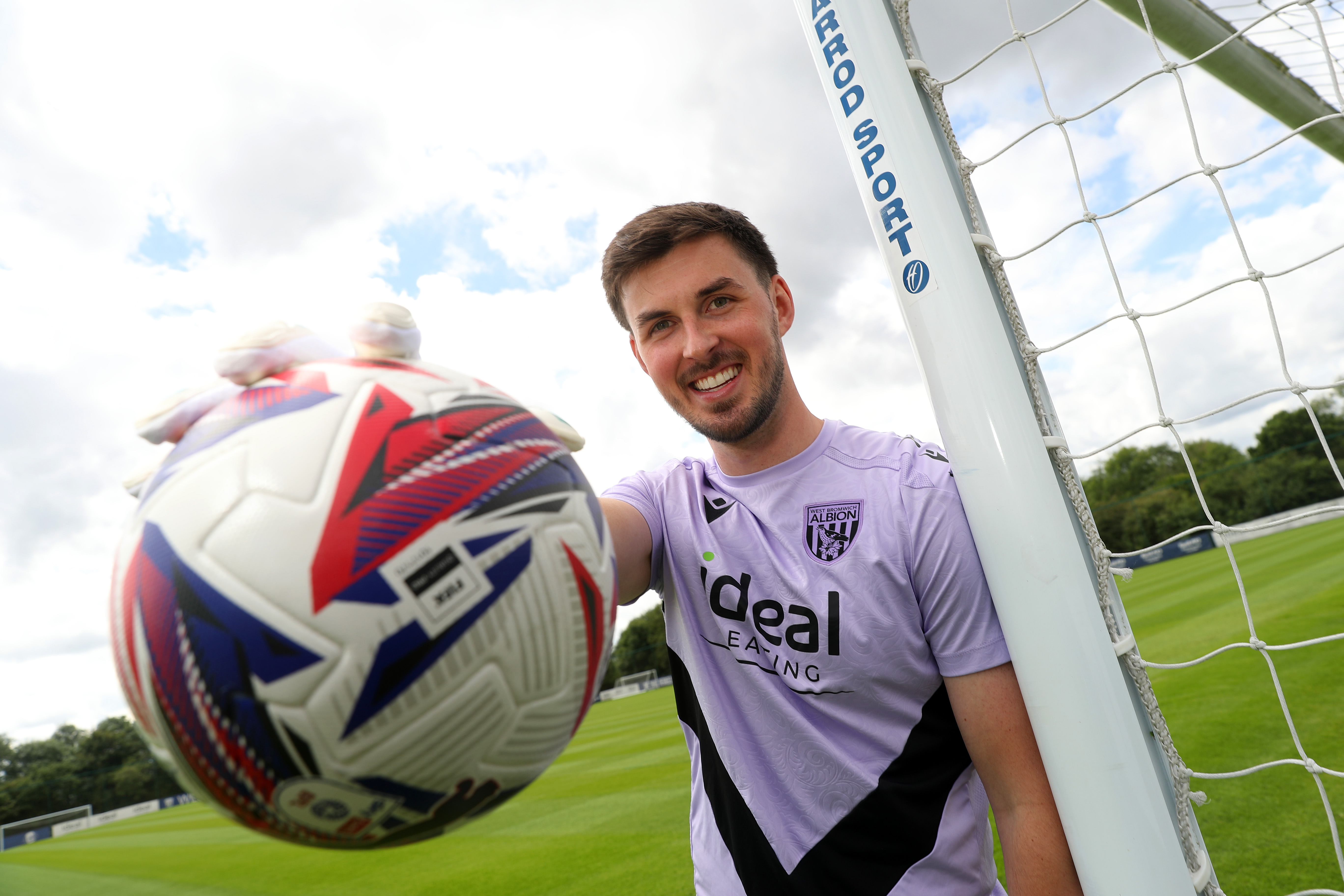 Joe Wildsmith smiling at the camera while holding a football