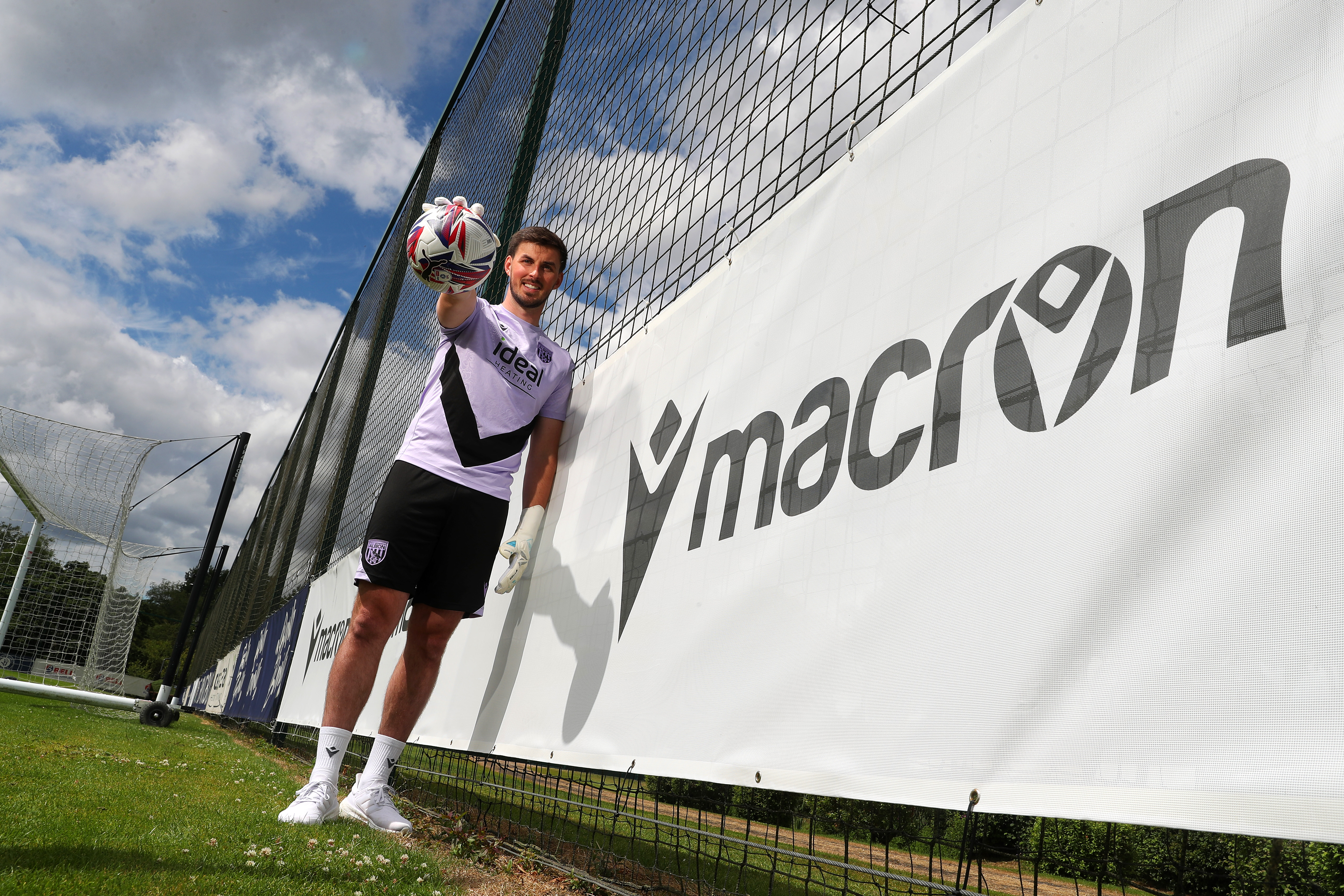 Joe Wildsmith smiling at the camera while holding a football