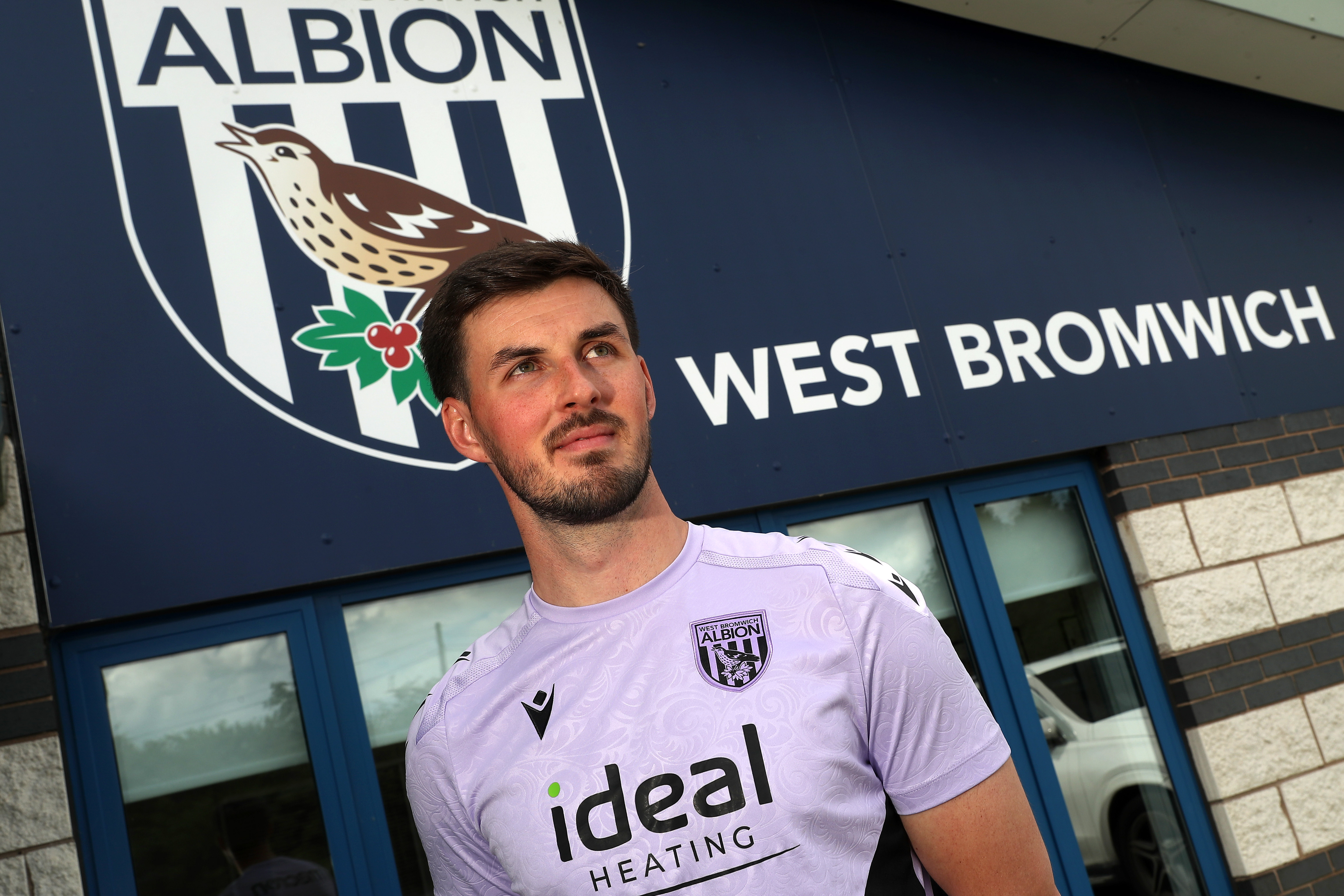 Joe Wildsmith stood in front of Albion branding at the training ground 