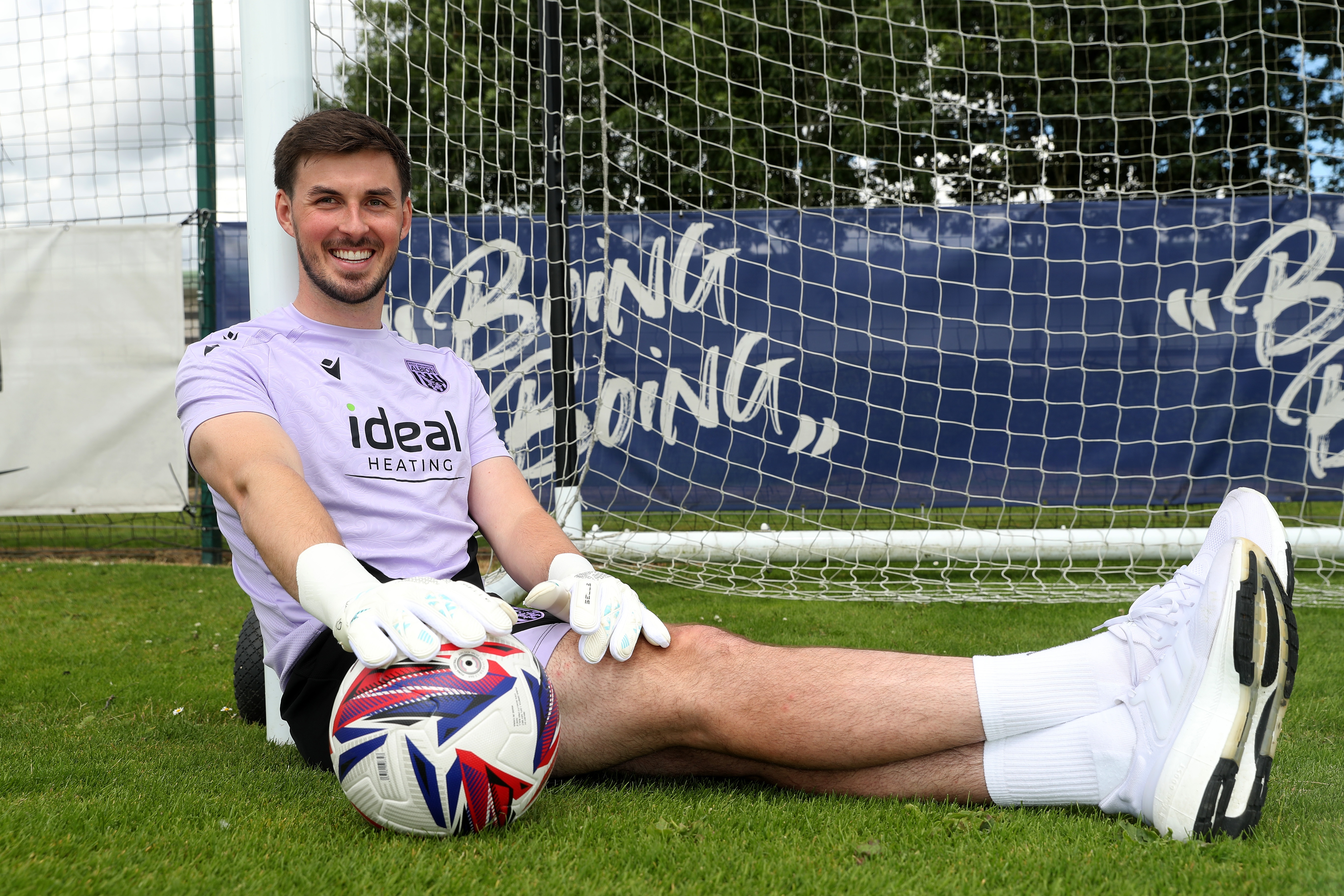 Joe Wildsmith sat on the pitch with the ball by his foot