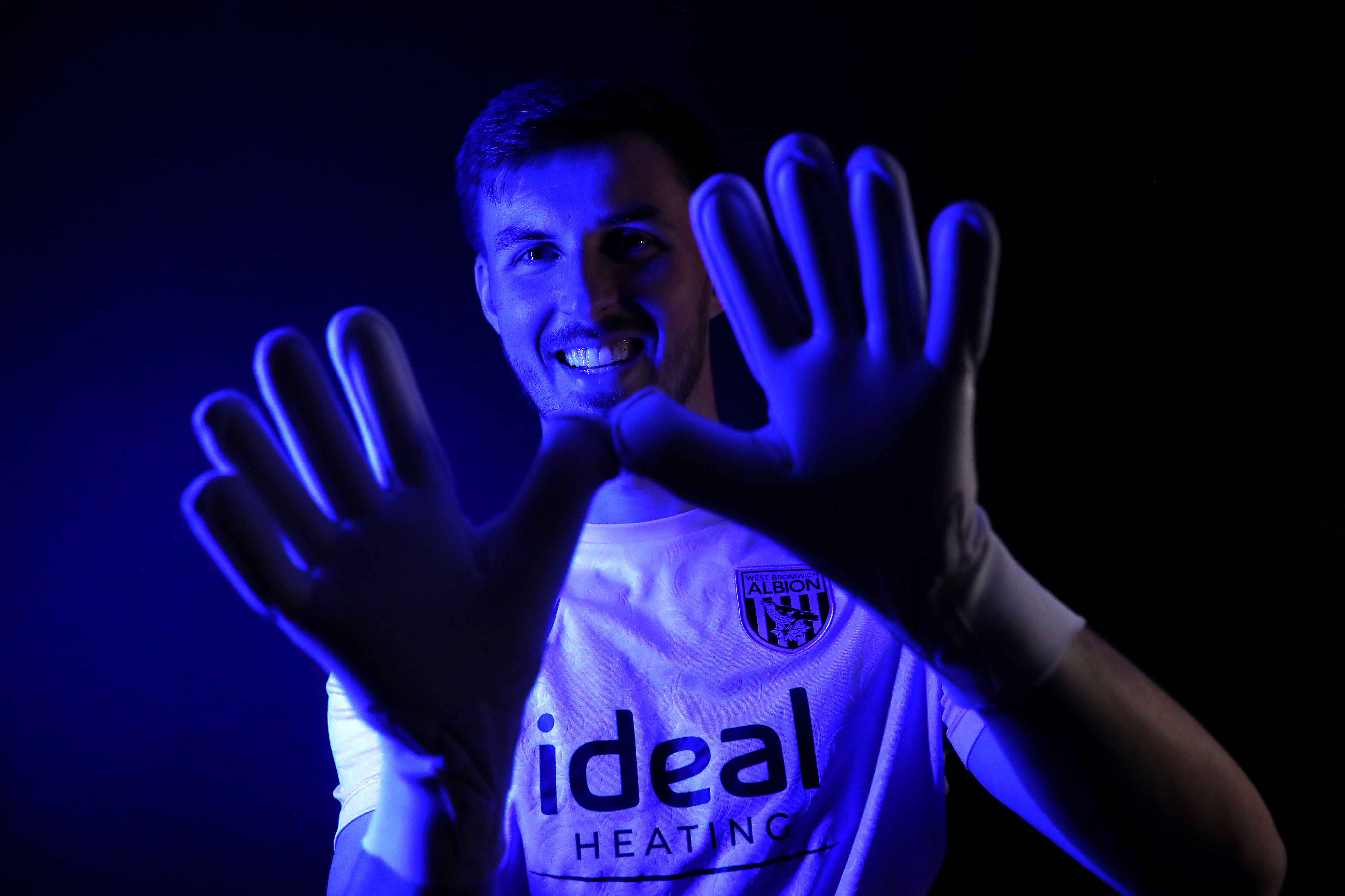 Joe Wildsmith holding his gloves up while looking at the camera smiling 