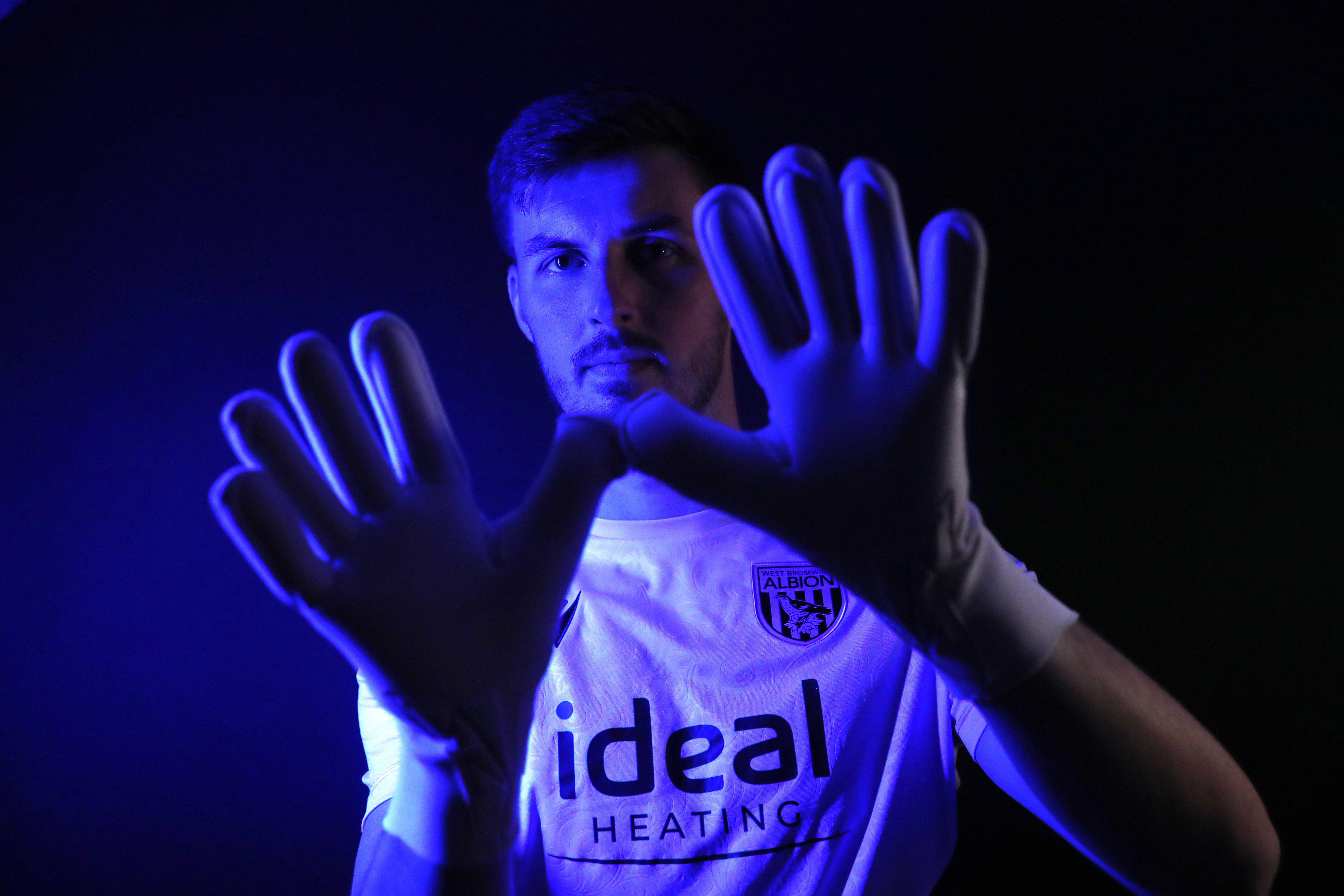 Joe Wildsmith holding his gloves up while looking at the camera 