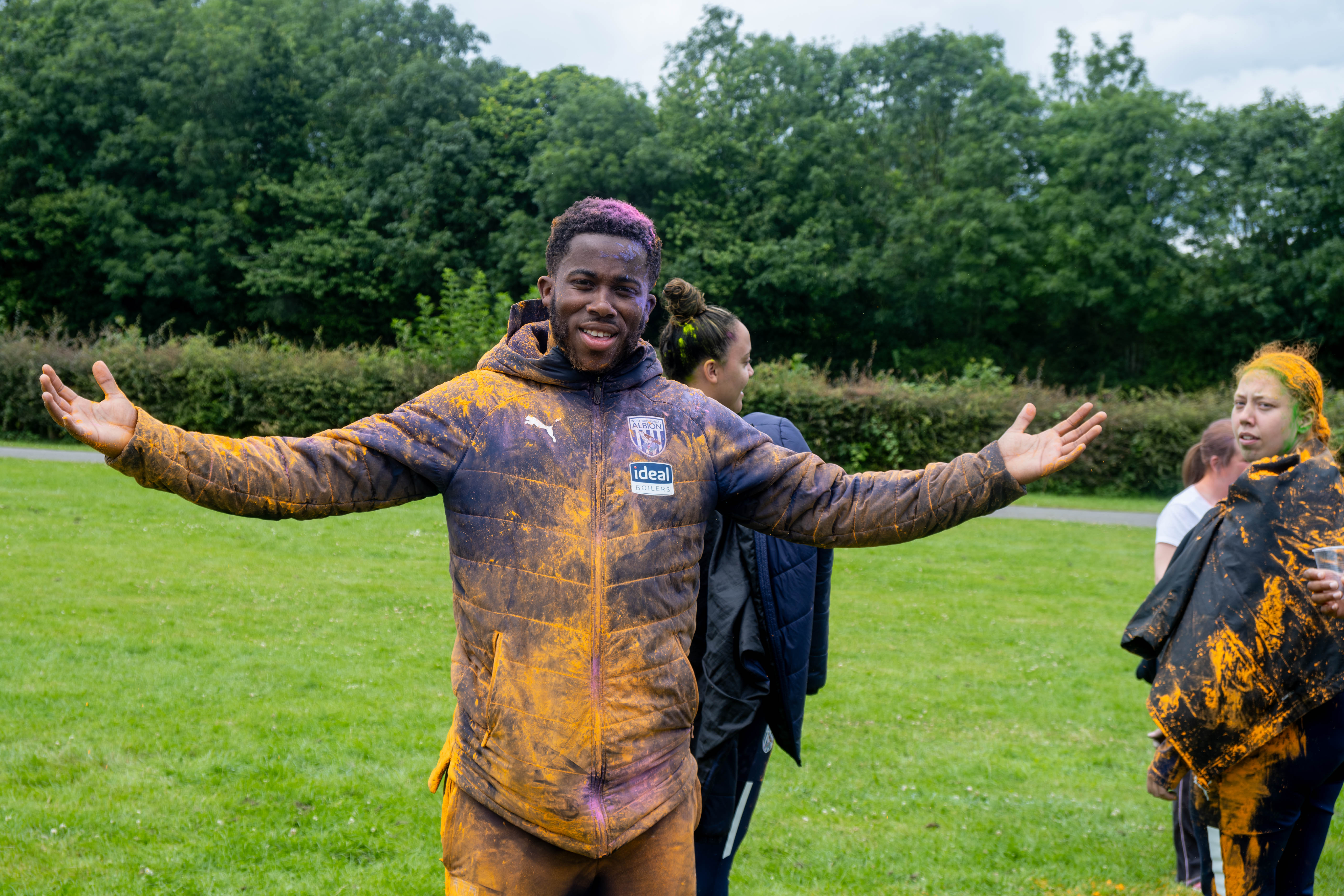 Foundation staff, with arms out, covered in paint.