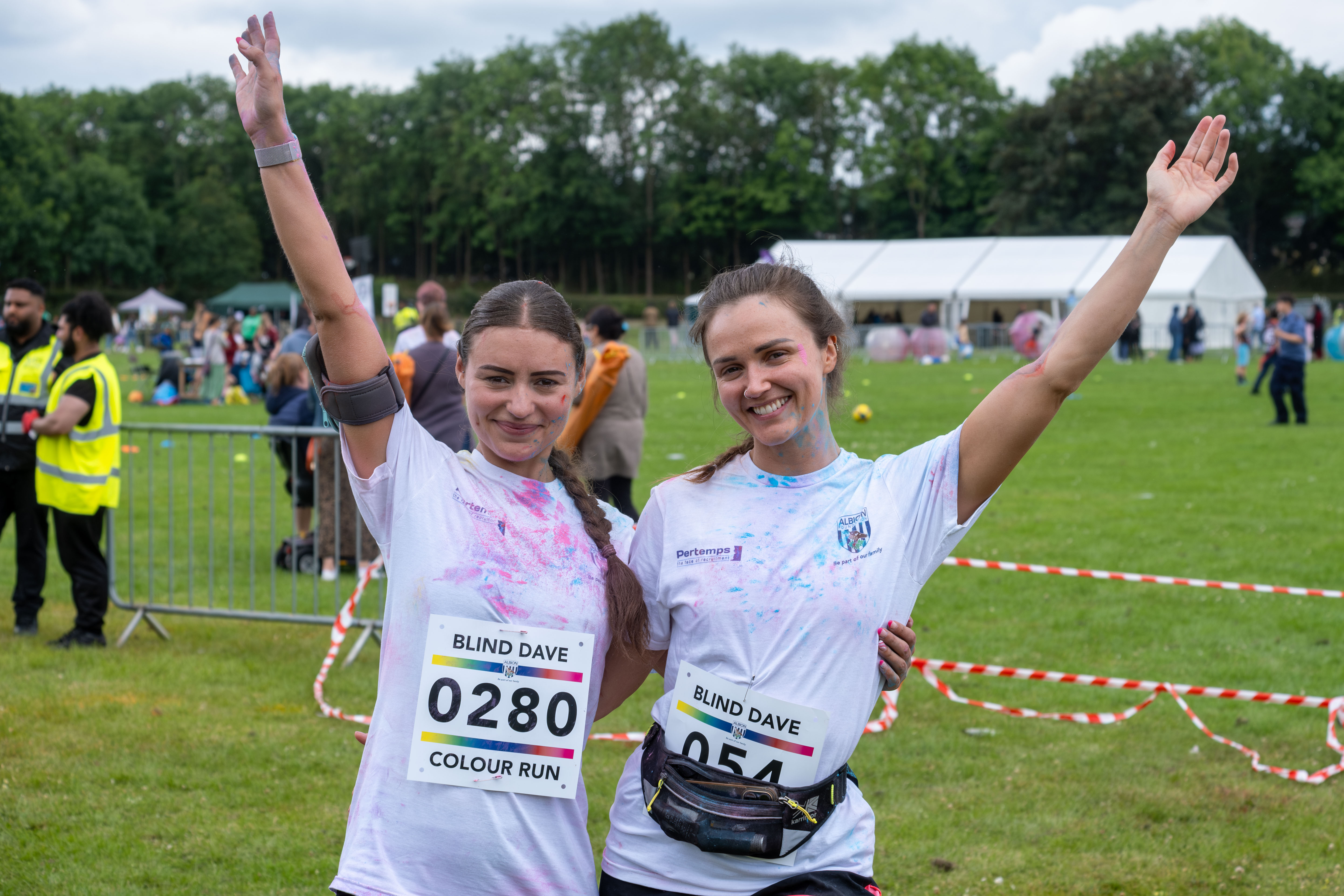 Two female participants, arms around one another and outer arms raised, pose for photo.