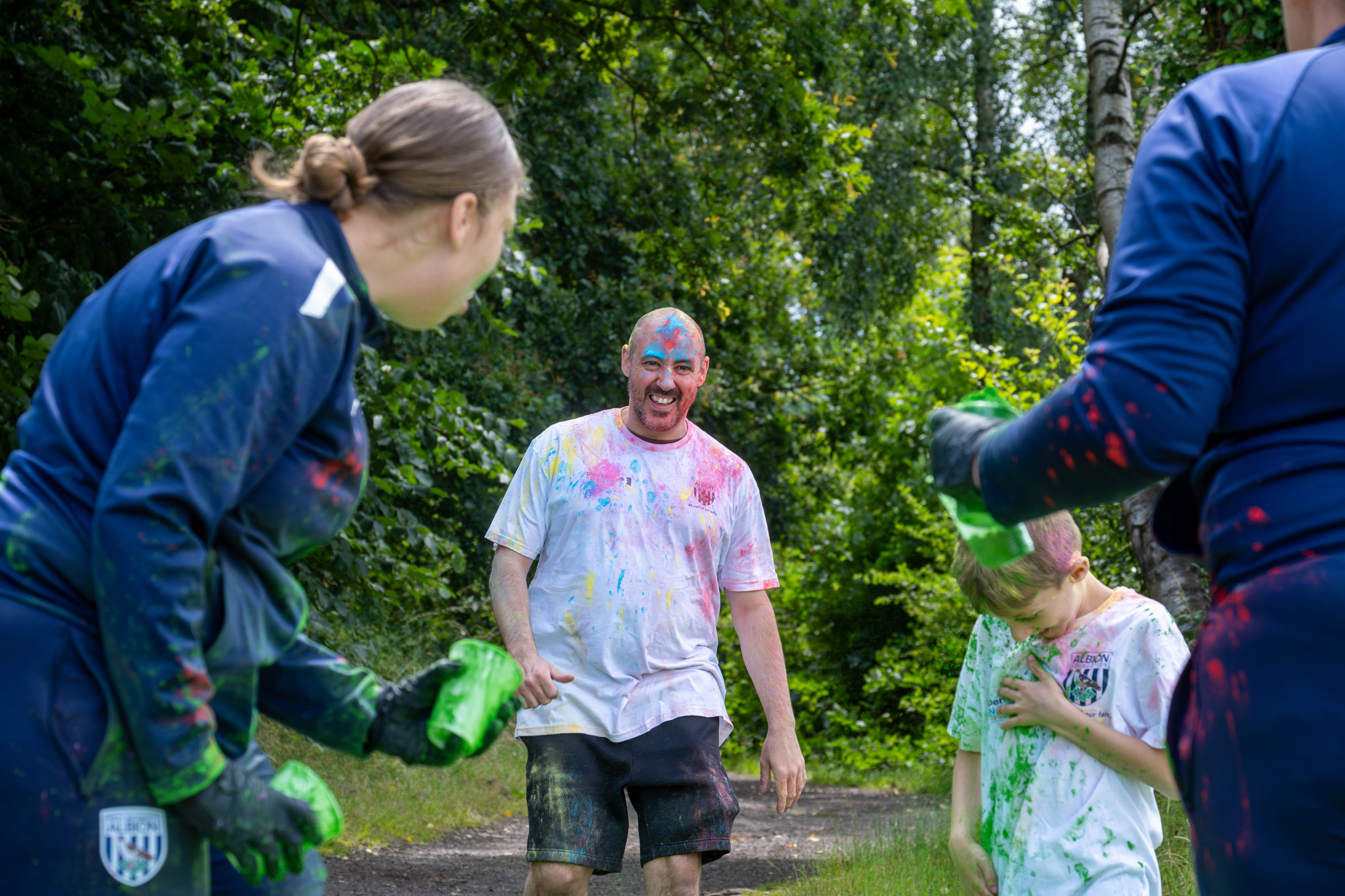 Father & Son running towards Foundation staff at a colour station, throwing paint powder.