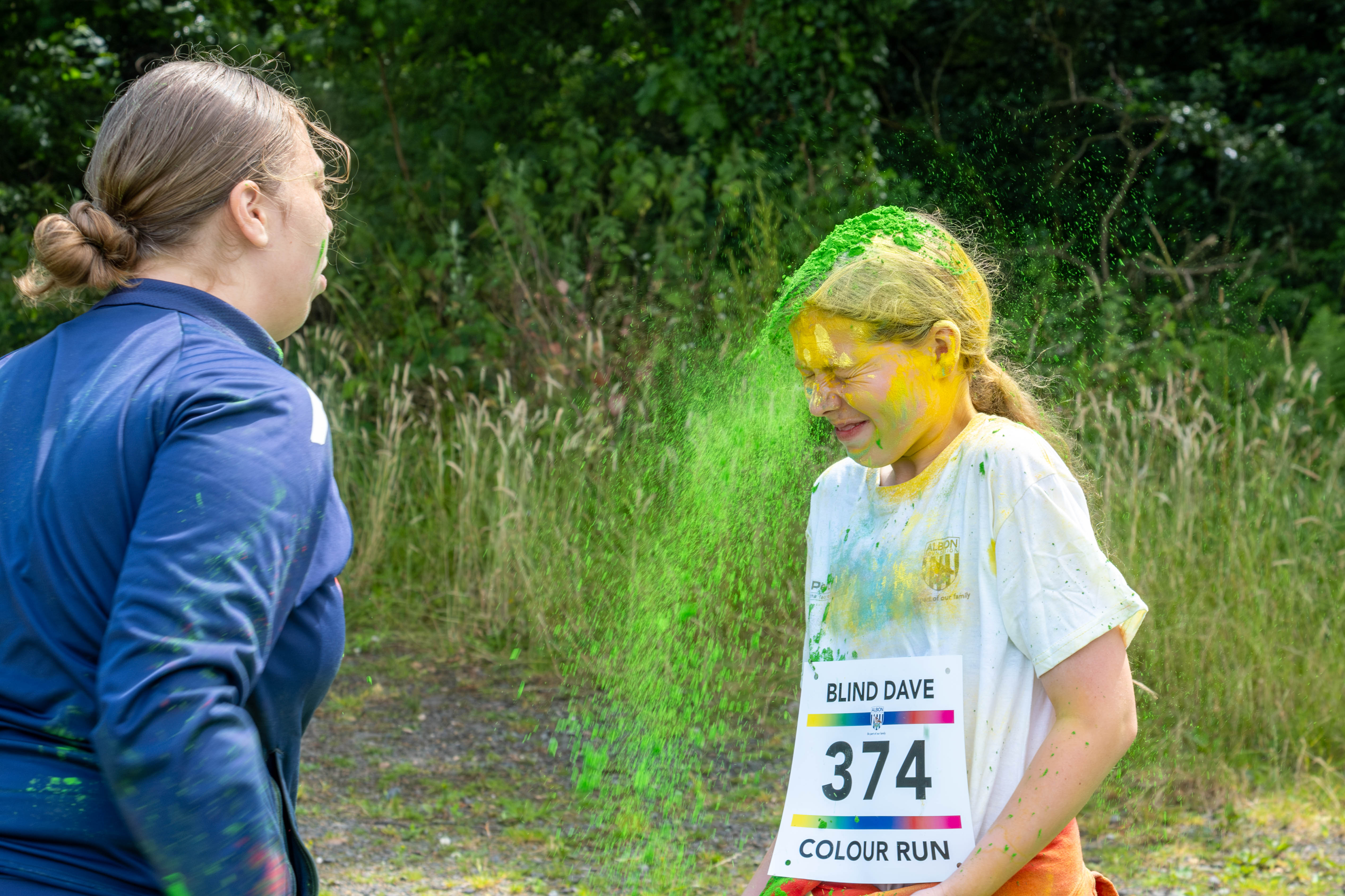 Young participant with a burst of green paint powders falling off of her hair.