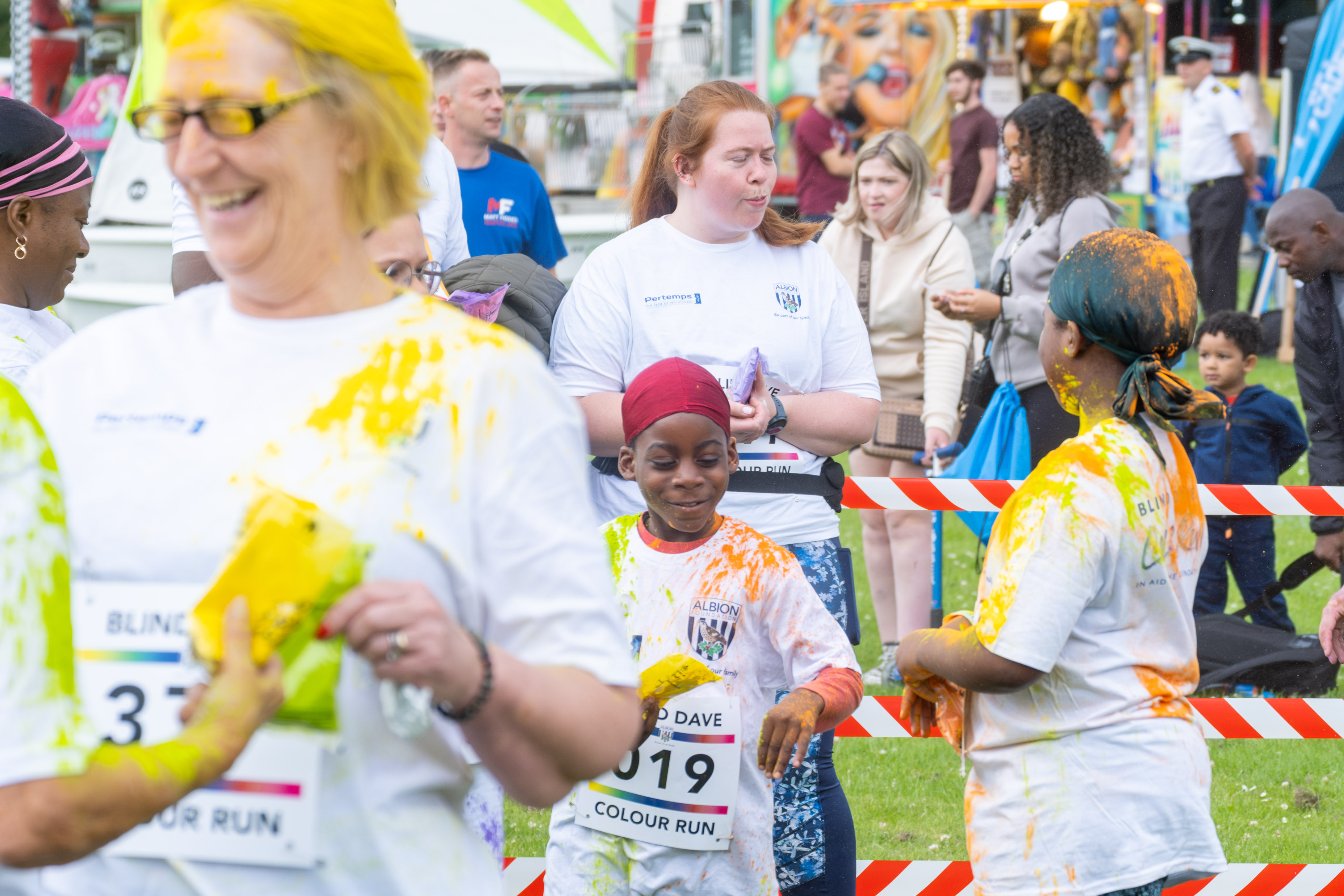 Group of participants and smiling inside barrier throwing paint powder.