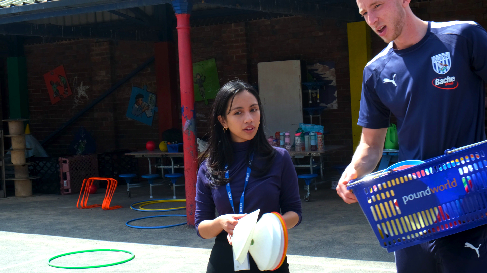 Miss Mendoza and Jordan Hill holding PE equipment.