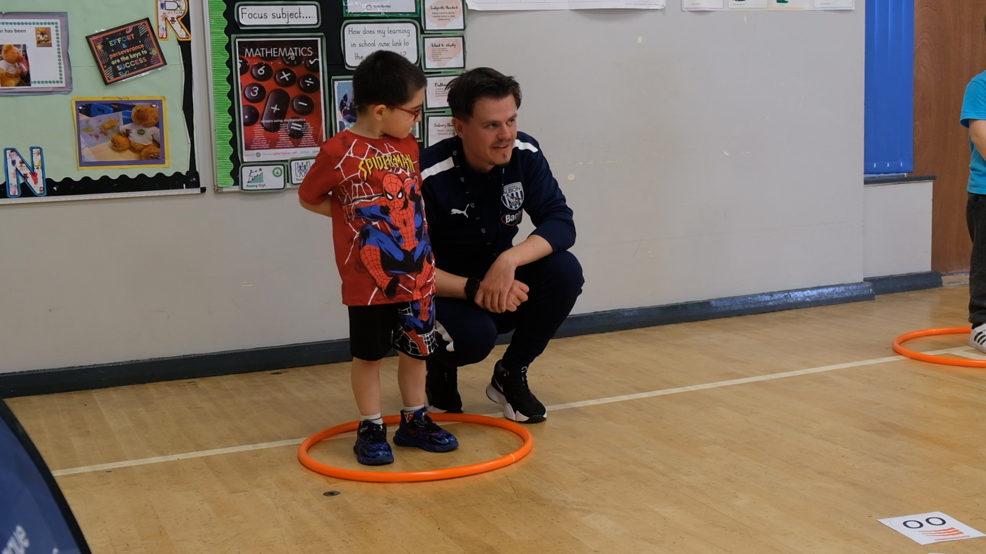 Abel and Greg Warren talk through an activity whilst Abel stands in a hula hoop.