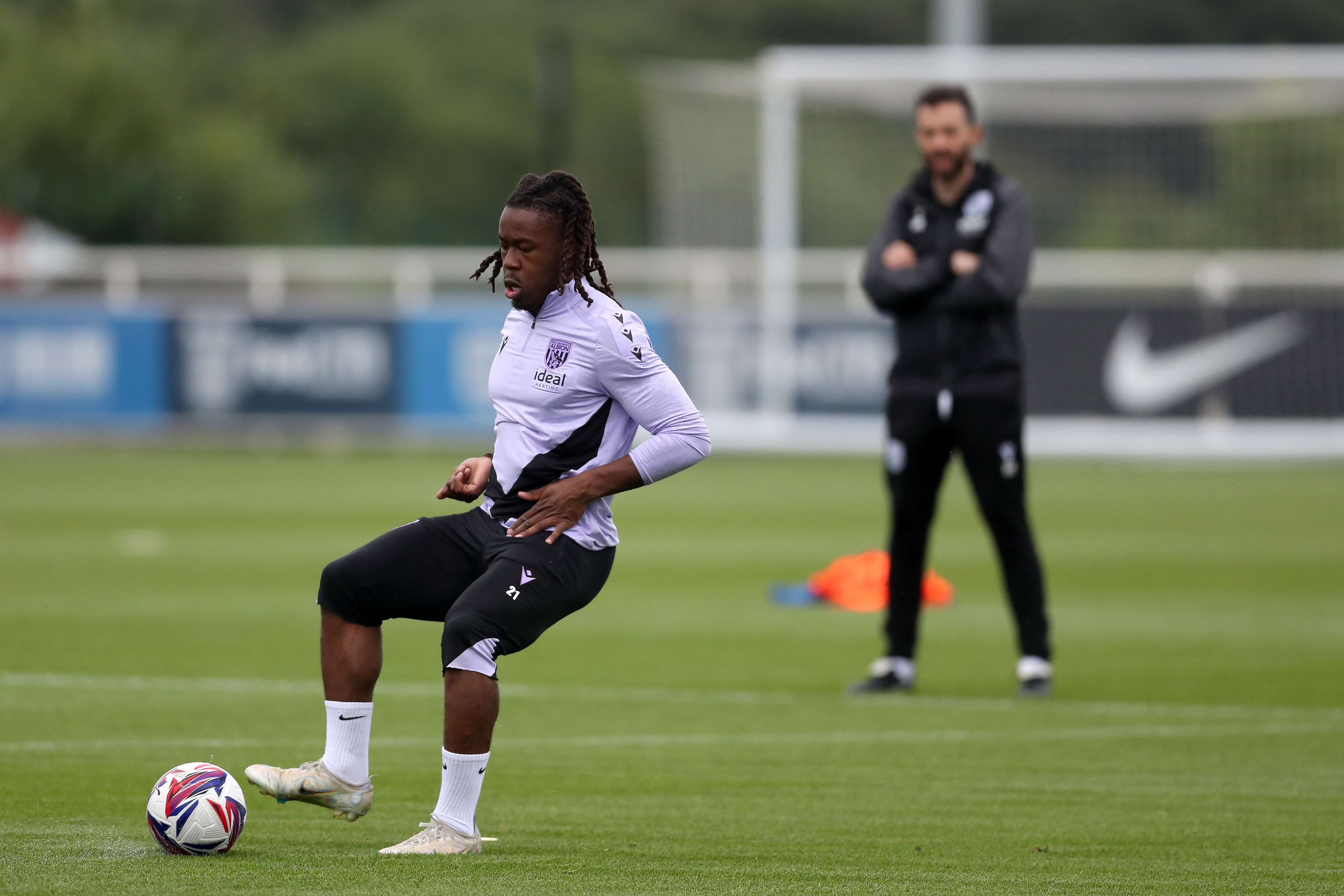 Brandon Thomas-Asante passing a ball during a training session with Carlos Corberán watching in the background