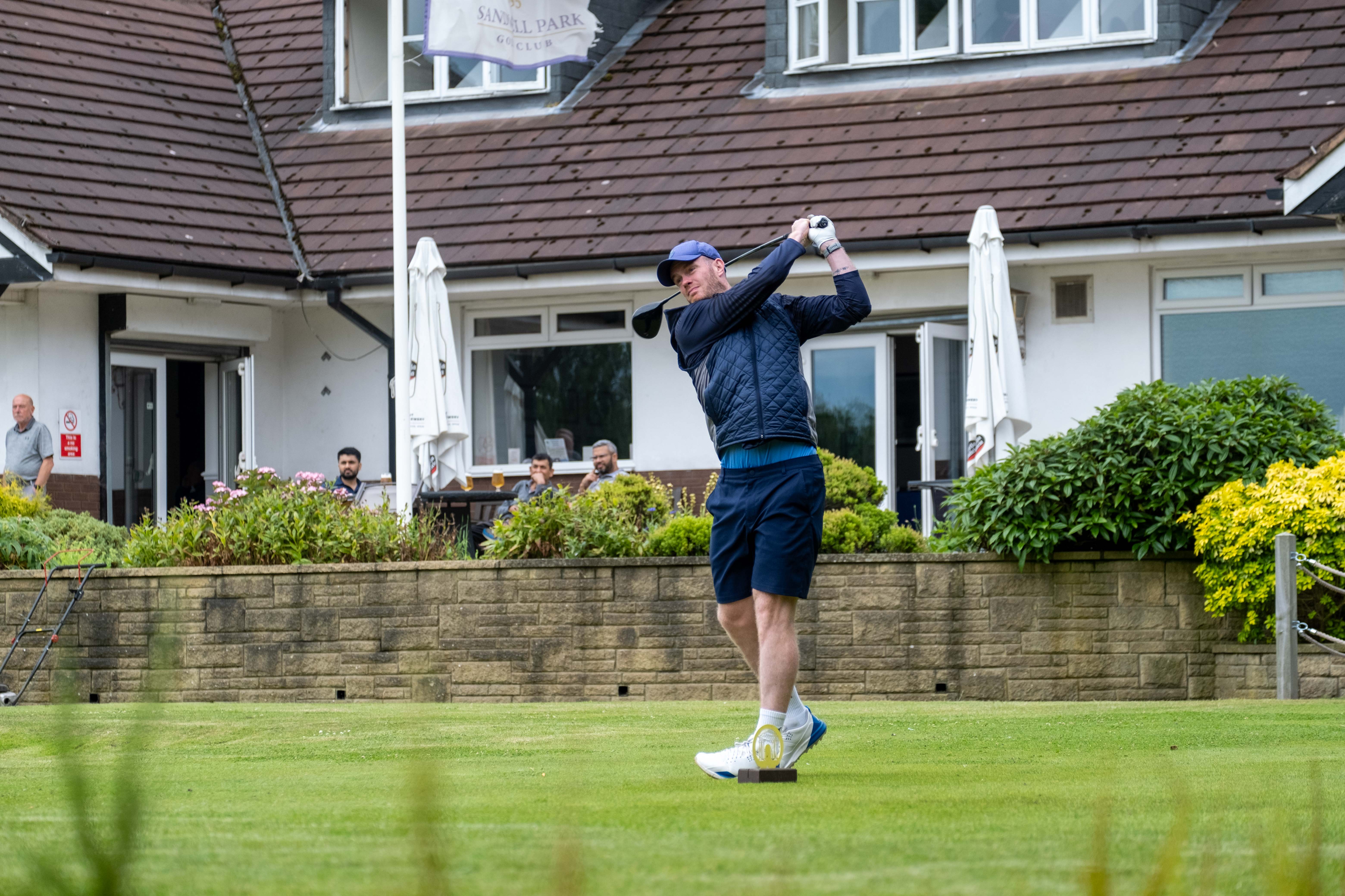 West Bromwich Albion legend Chris Brunt takes a swing in front of the Sandwell Park Golf Club pavilion.