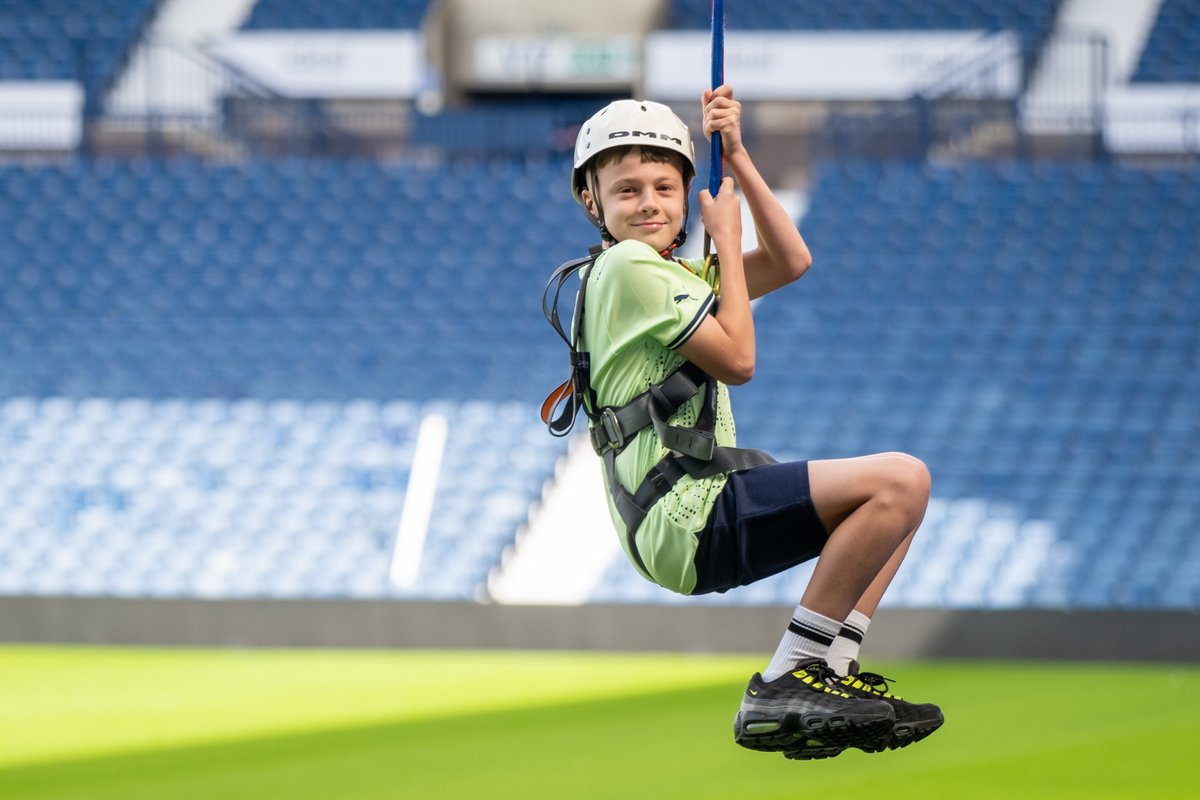 A child soars across The Hawthorns holding onto the Zipwire with two hands.