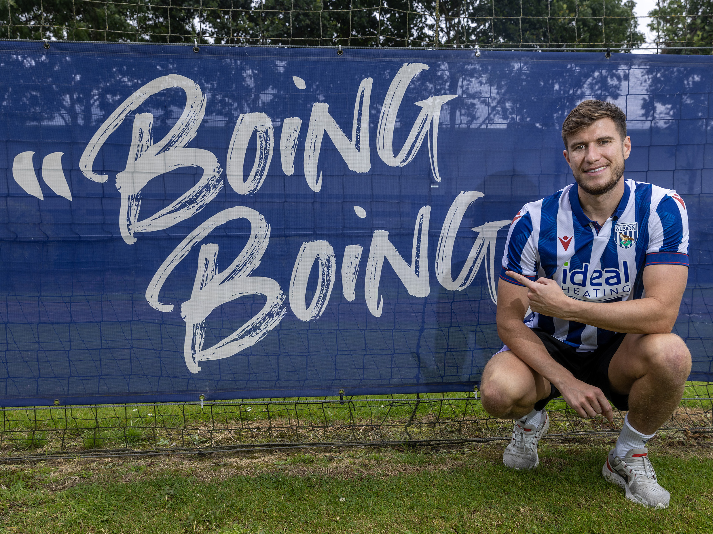 Paddy McNair smiling at the camera while crouched down wearing a home shirt in front of a 'Boing Boing" sign 