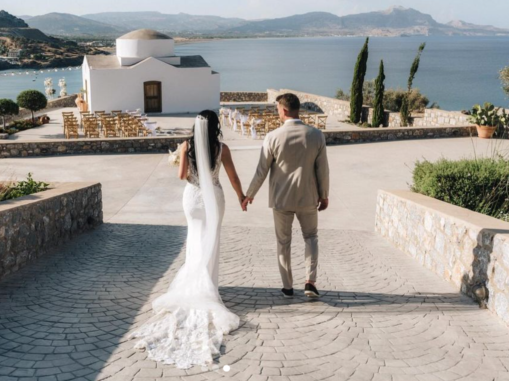 An image of Alex Palmer and his wife Penny holding hands on their wedding day