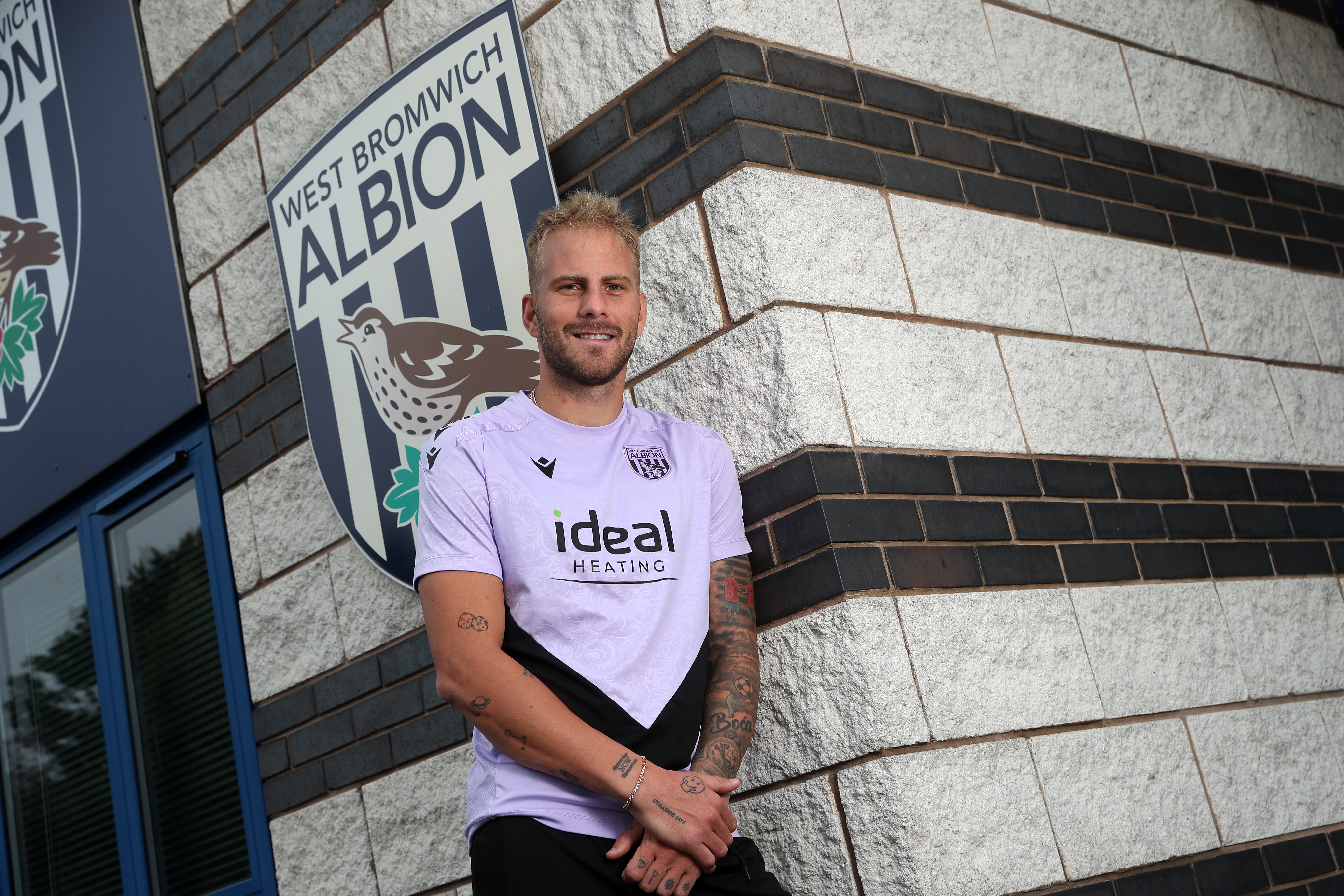 Uroš Račić smiling at the camera while stood outside the front of the training ground 