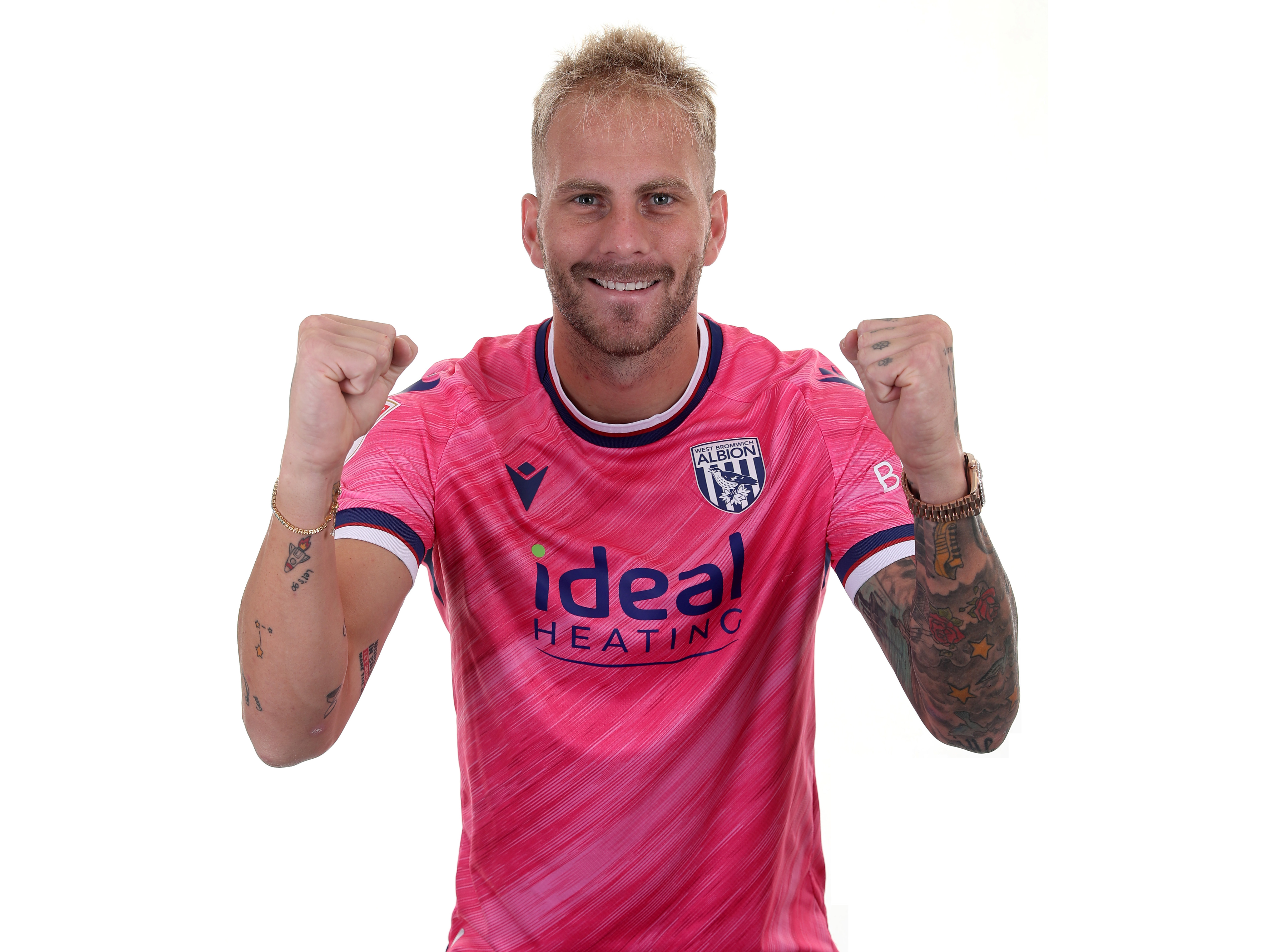 Uroš Račić smiling at the camera while celebrating in the pink away shirt 