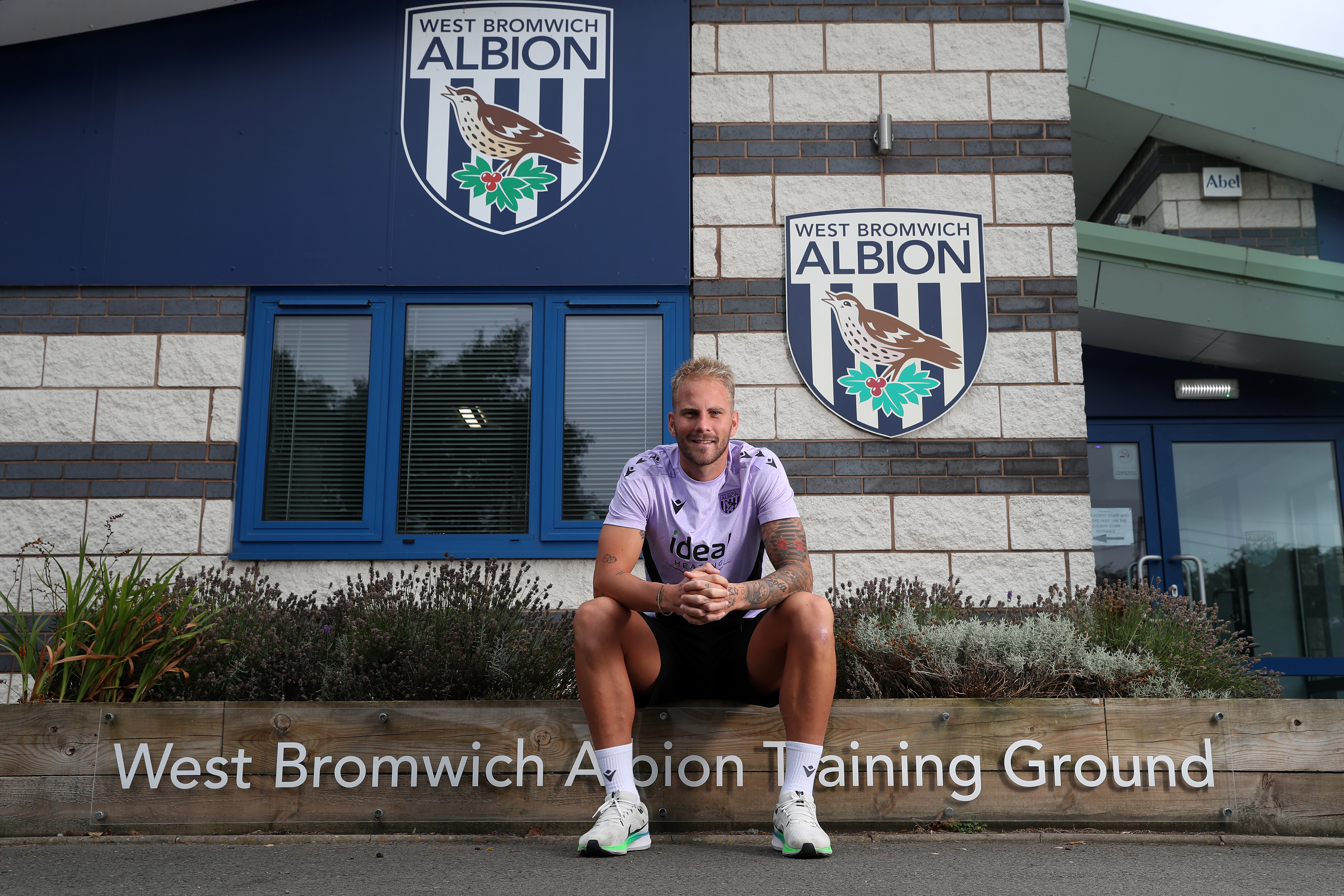 Uroš Račić smiling at the camera while sat outside the front of the training ground 