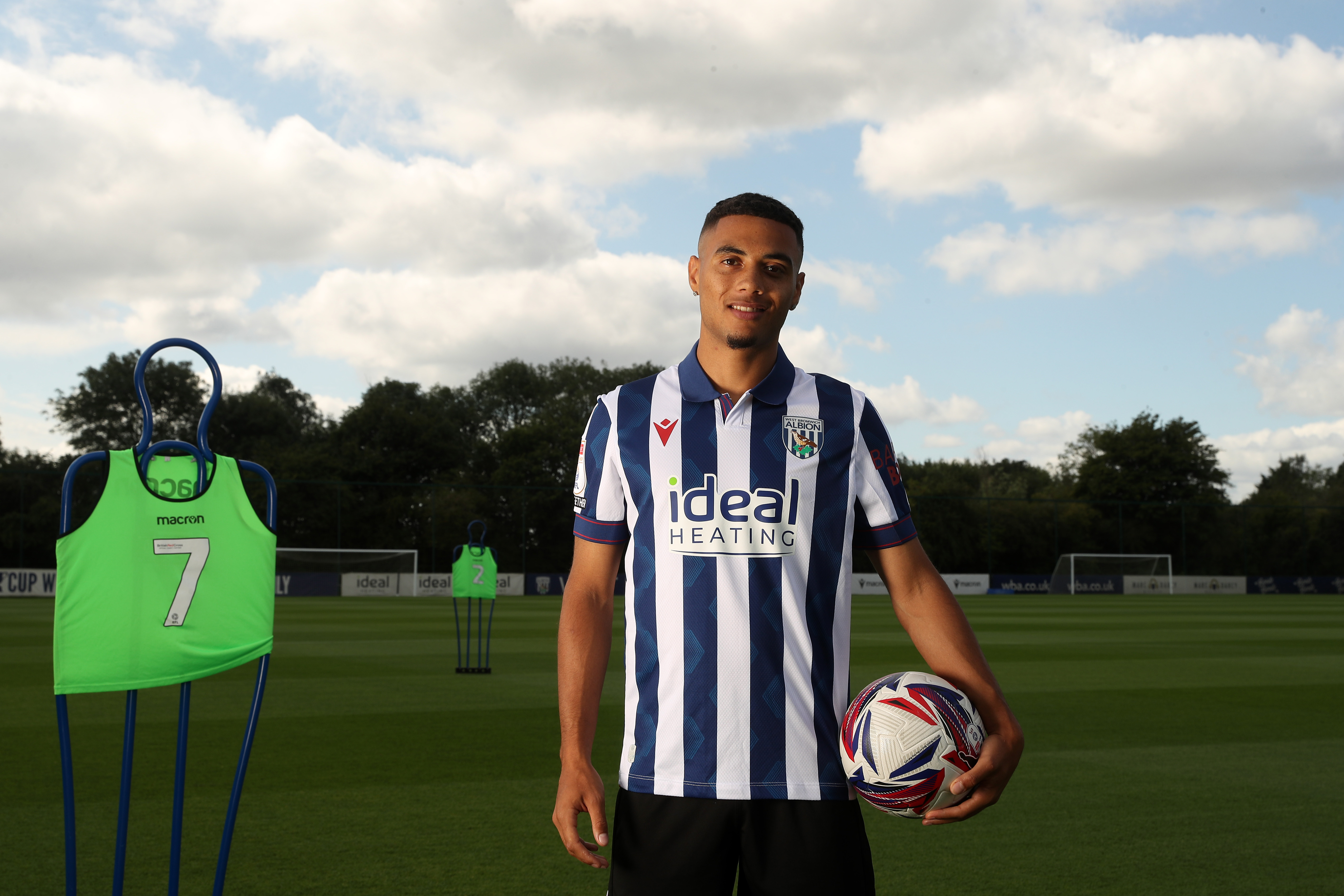 Lewis Dobbin looking at the camera while stood on the training pitch in a home shirt with a ball in his hand 