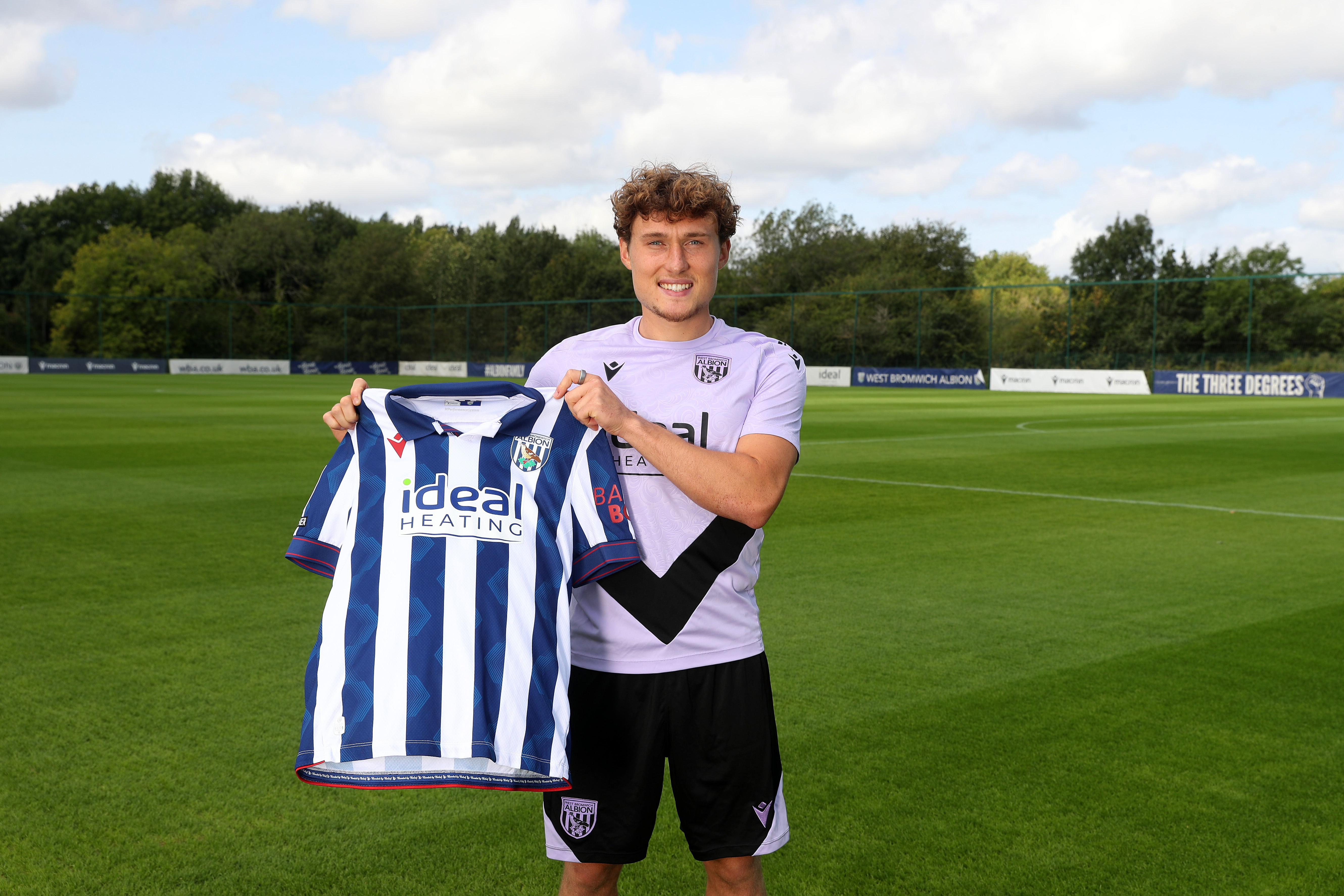 Callum Styles smiling at the camera while holding a home shirt 