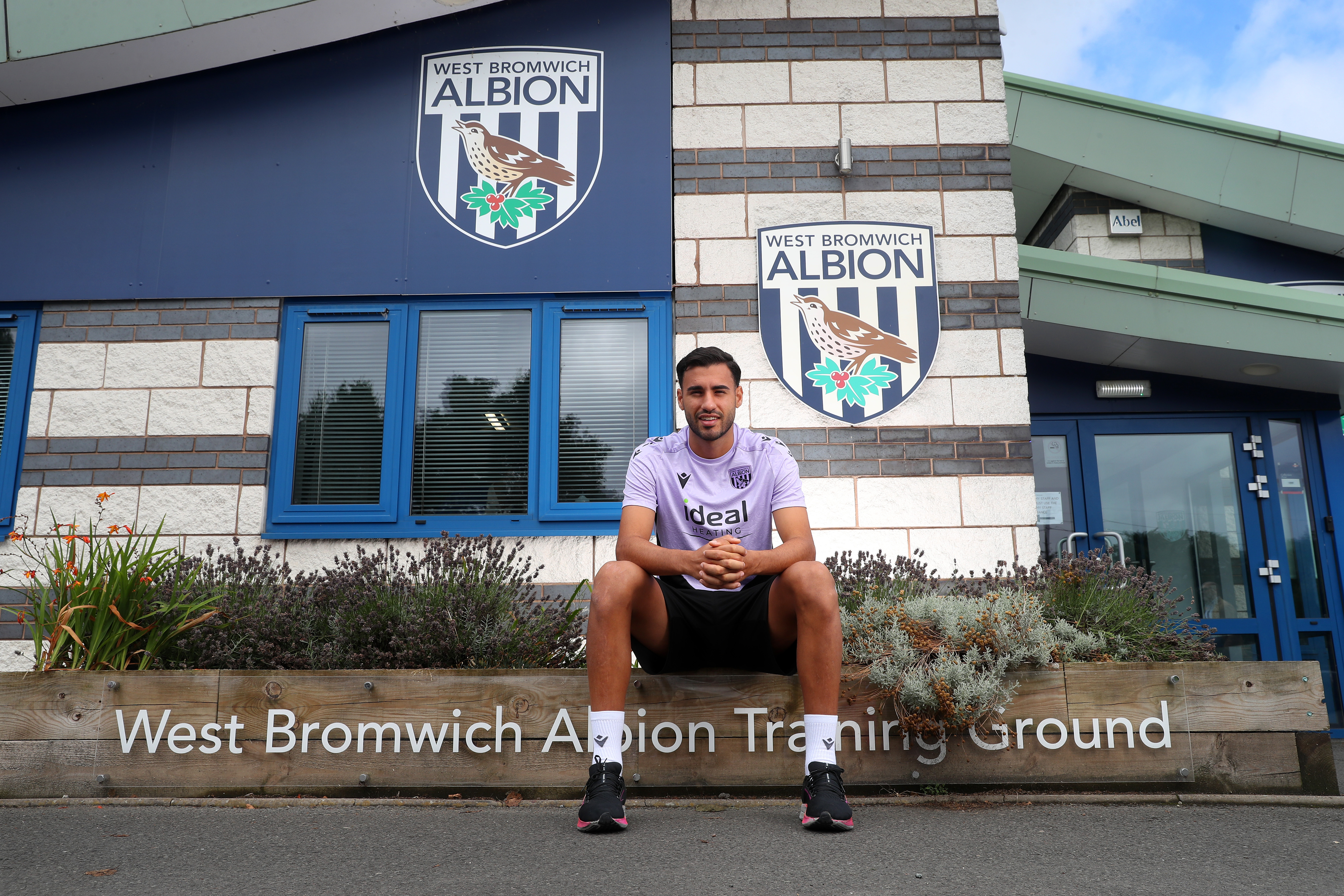 Gianluca Frabotta smiling at the camera while sat outside the front of the training ground 