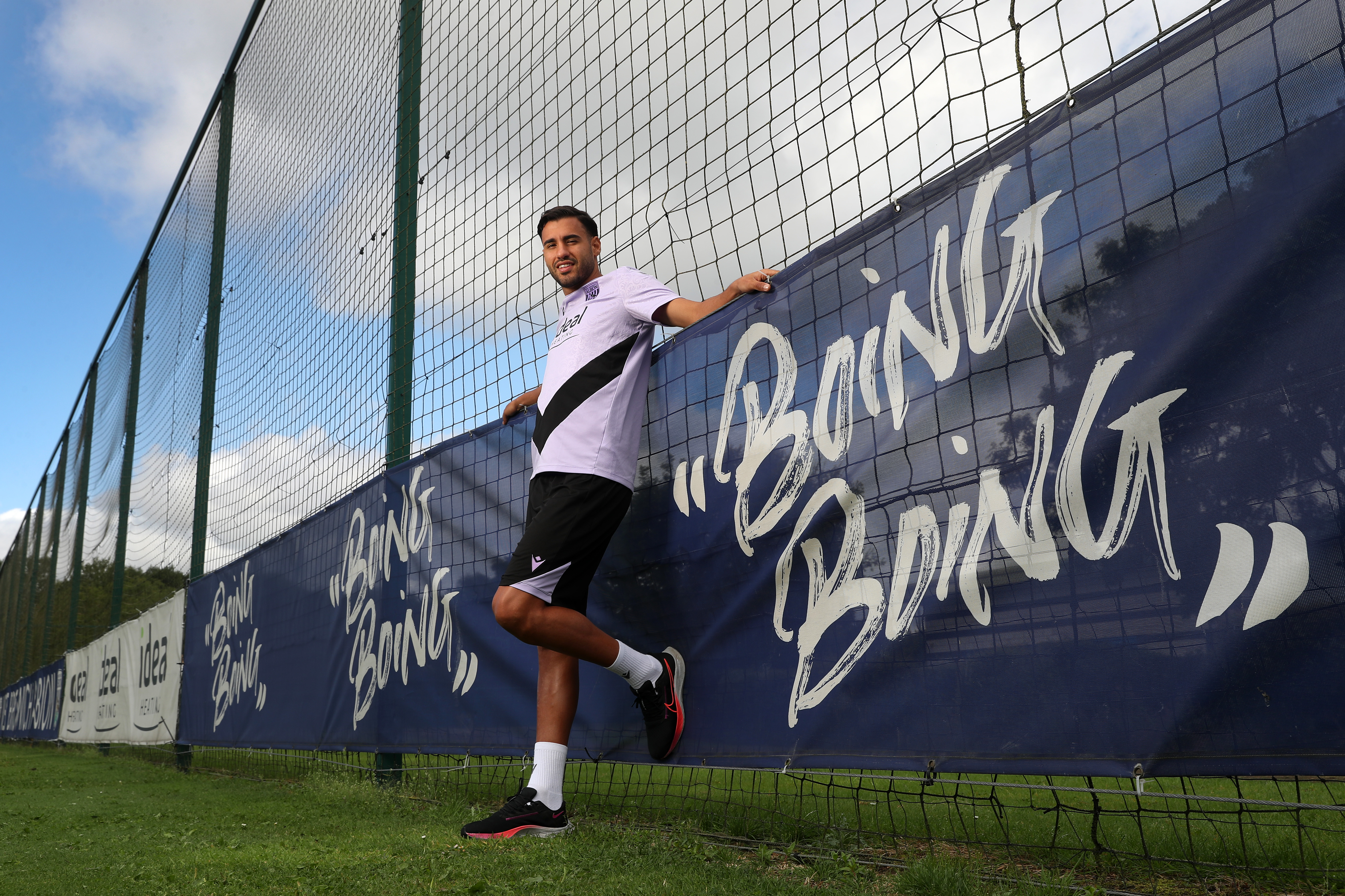 Gianluca Frabotta smiling at the camera while stood next to branding around a pitch which reads boing boing