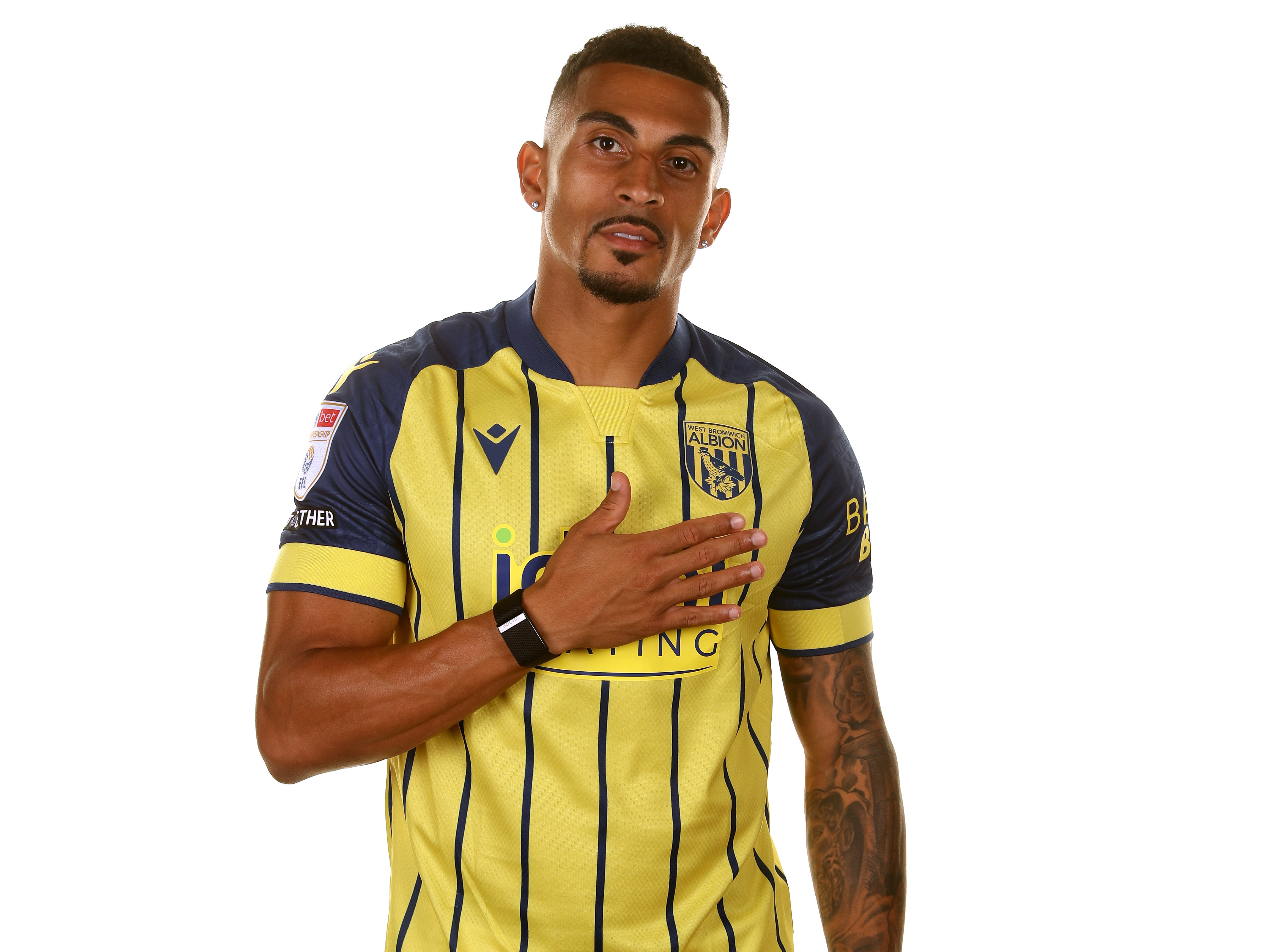 Karlan Grant with one hand on his chest looking at the camera wearing the yellow away shirt 