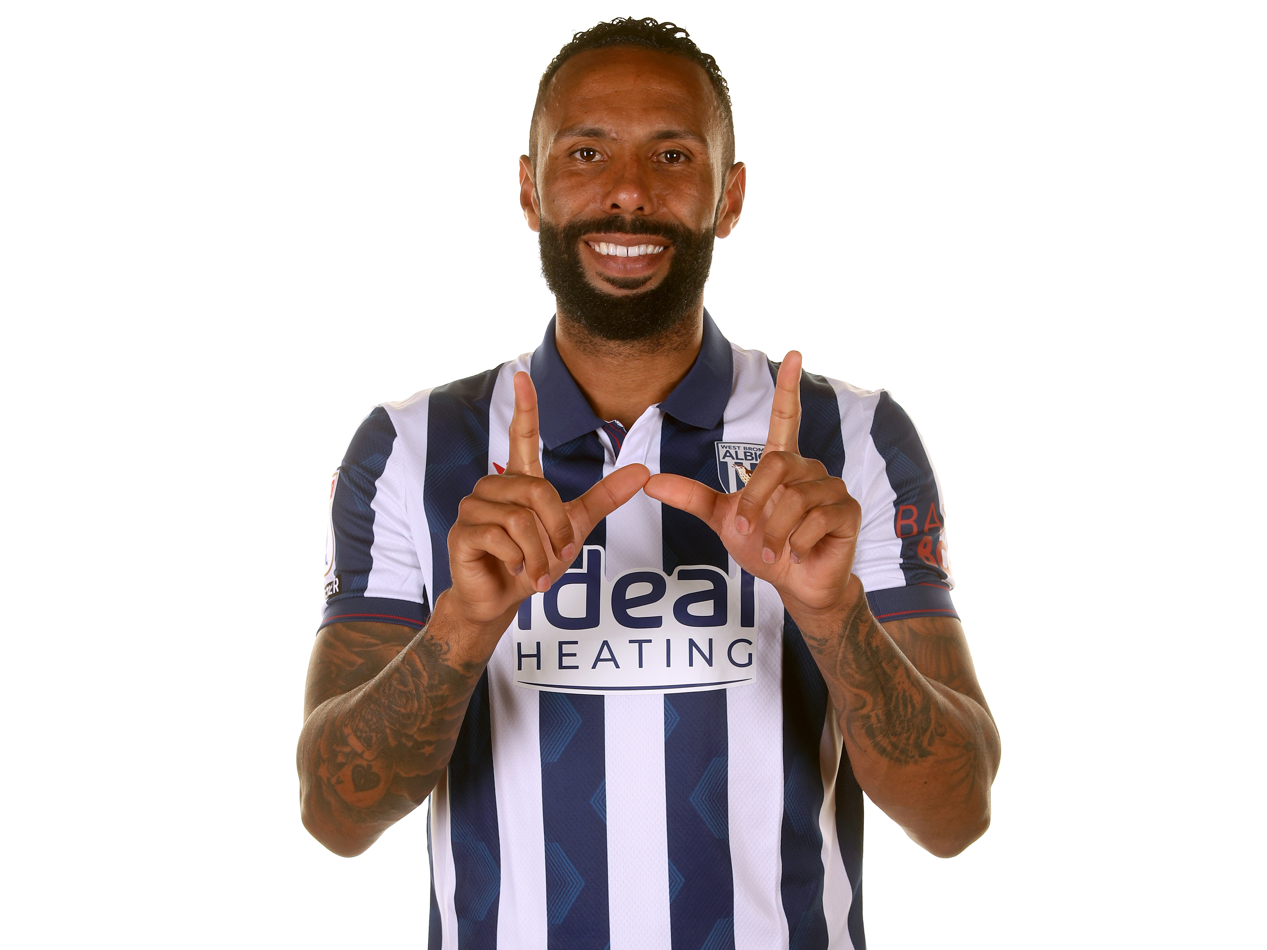 Kyle Bartley makes a 'W' sign while smiling at the camera in the home shirt 