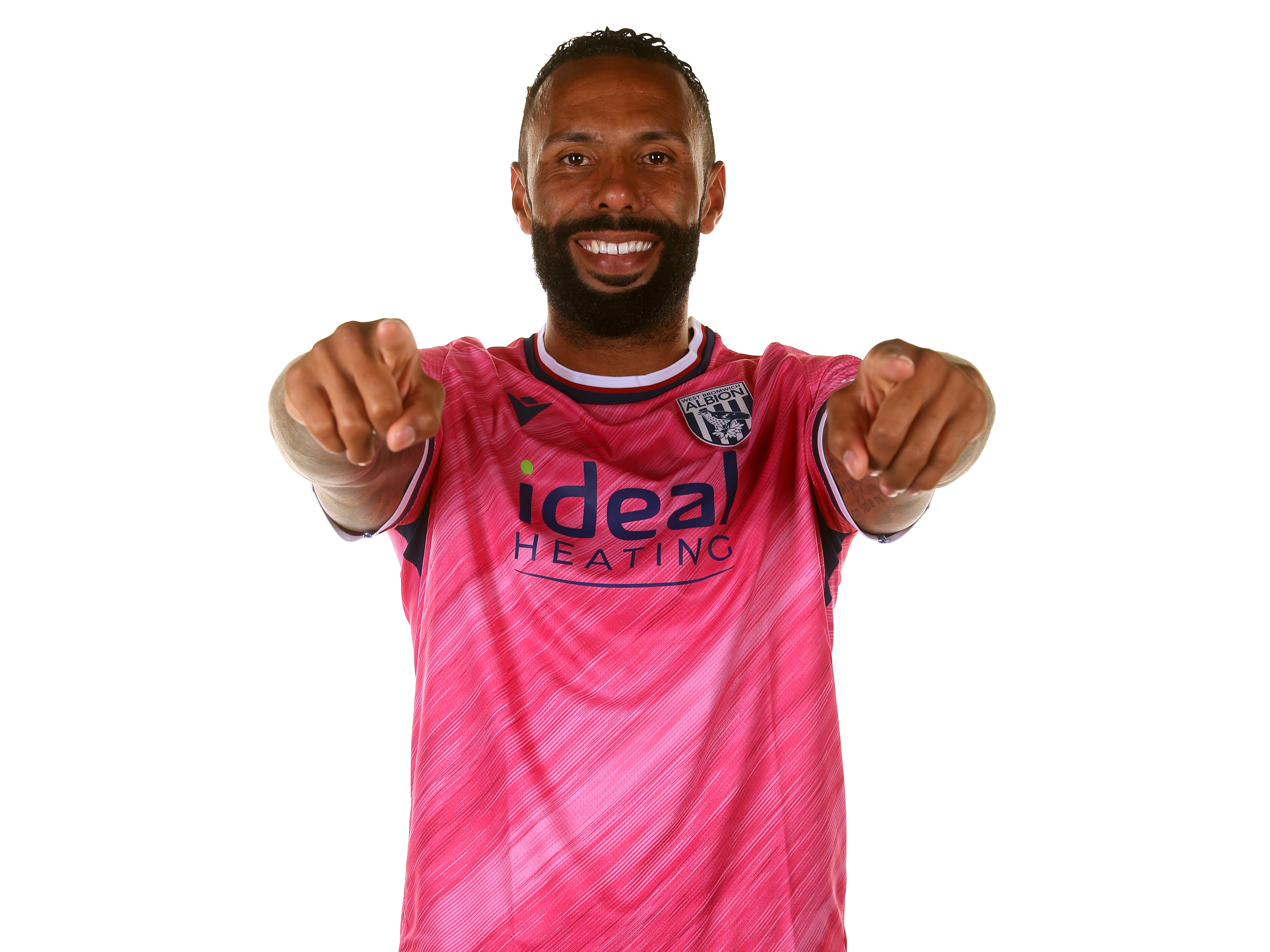 Kyle Bartley pointing and smiling at the camera wearing the pink away shirt 